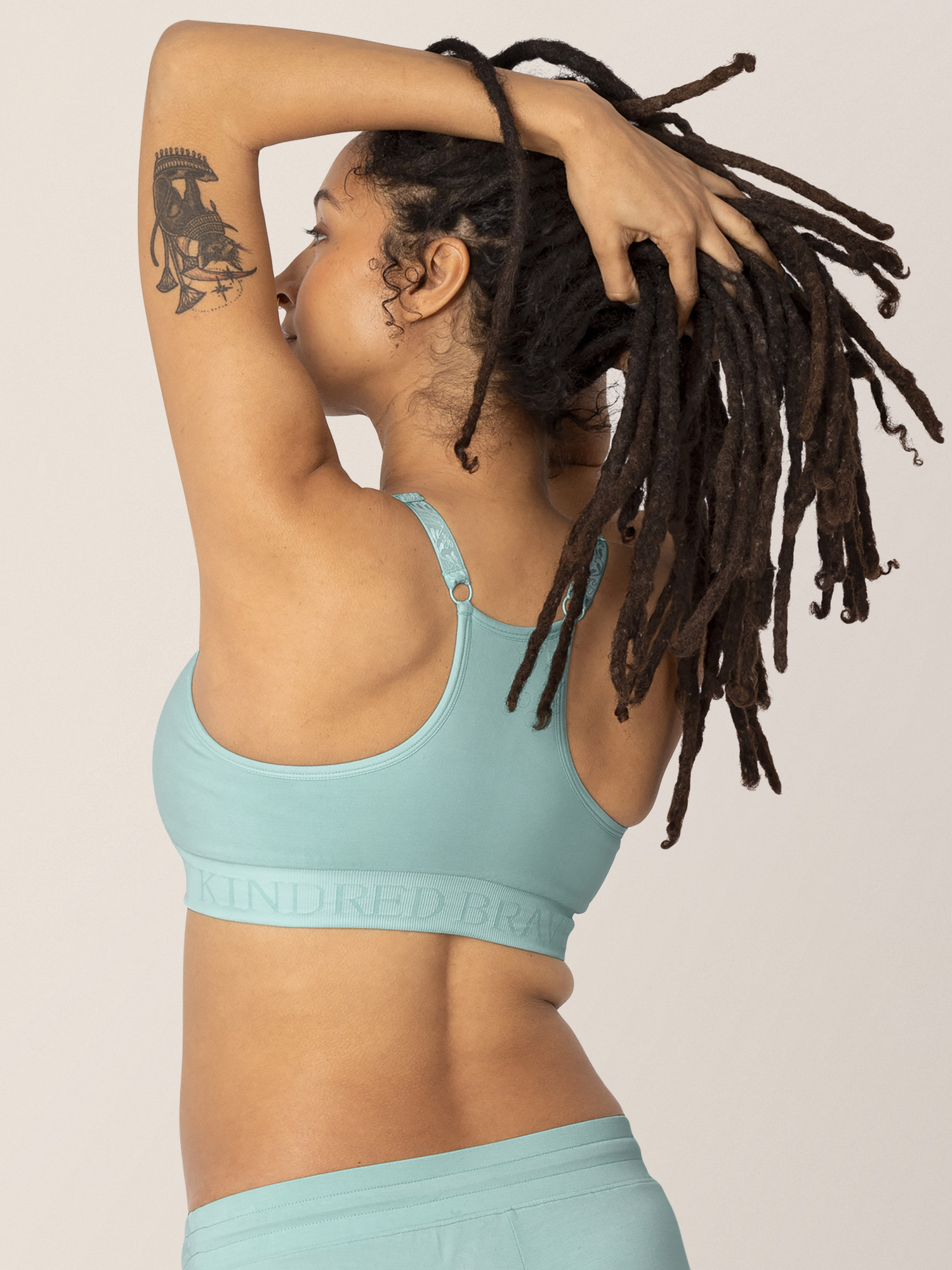 Back view of model wearing the Sublime® Hands-Free Pumping & Nursing Sports Bra in dusty blue green