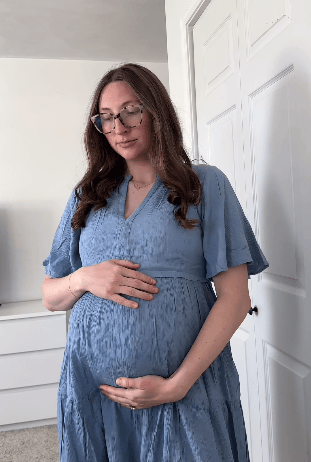 Rotating video of pregnant woman wearing Marlowe Maternity & Nursing Mini Dress in Vintage Blue in a light filled bedroom.
