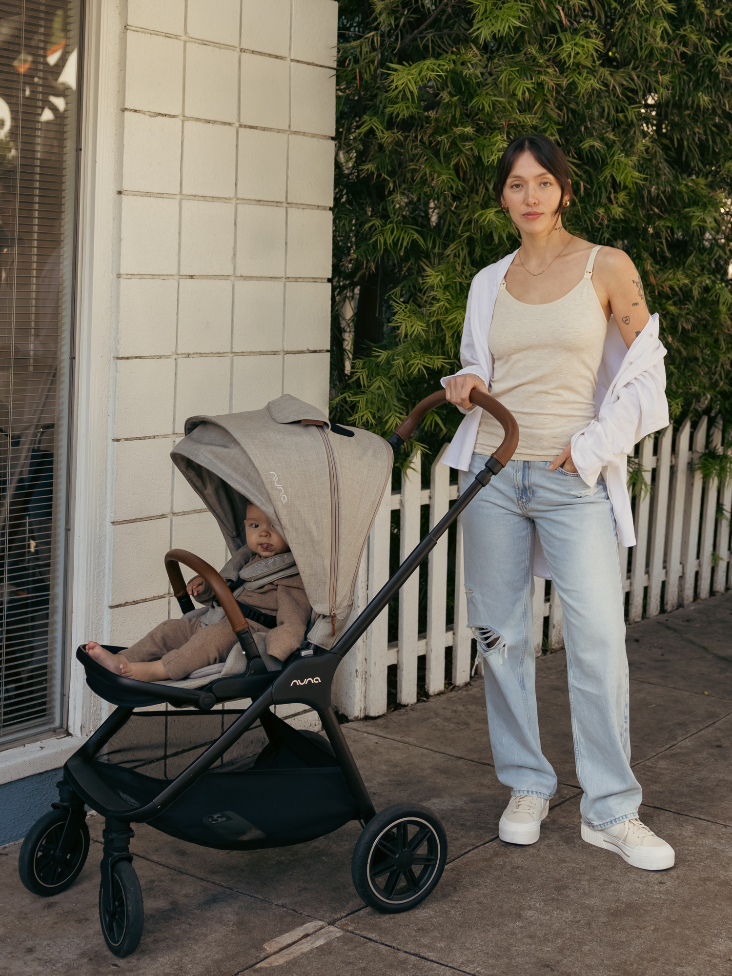 Model outside with baby in stroller, wearing the Sublime® Bamboo Maternity & Nursing Camisole in oatmeal heather, paired with an open button-down shirt and jeans.