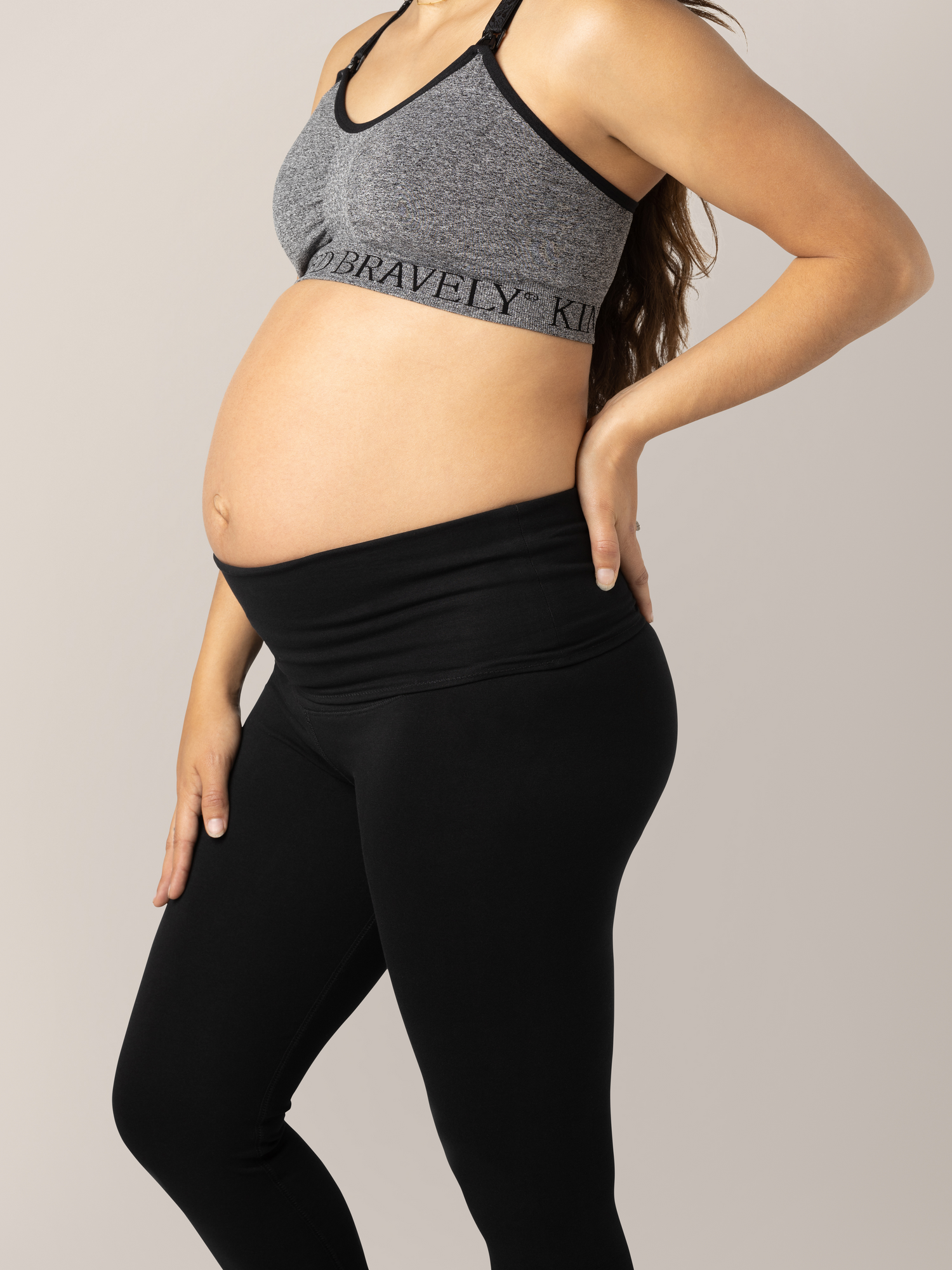 Close-up front view of waist band unfolded on the Cotton Maternity & Postpartum Footless Tight in black on pregnant model