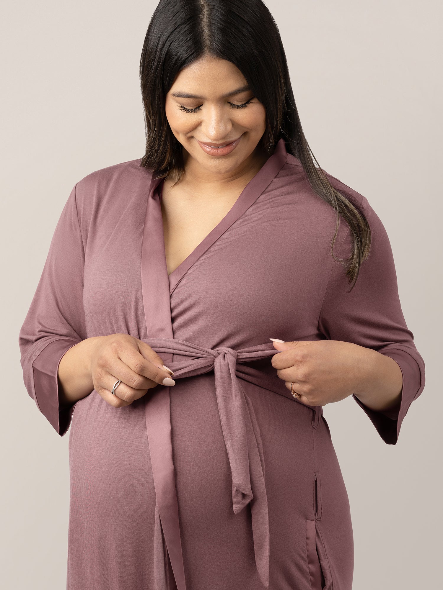 Closeup of a pregnant model wearing the Emmaline Robe in Twilight holding onto the tie