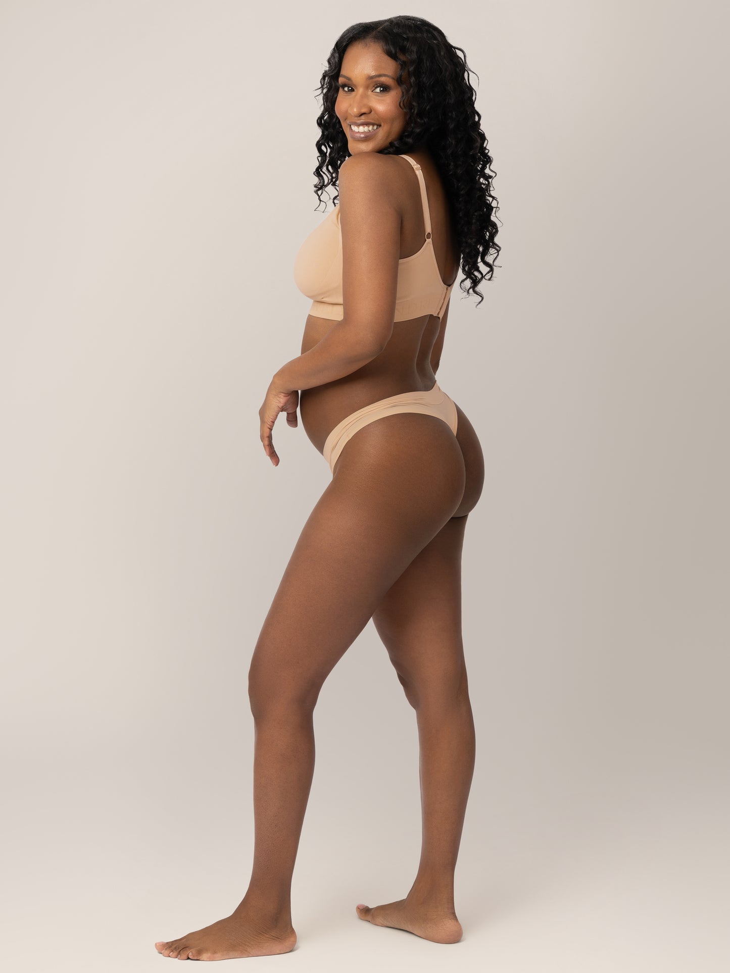 Side view of a model wearing the Grow with Me™ Maternity & Postpartum Thong in Beige