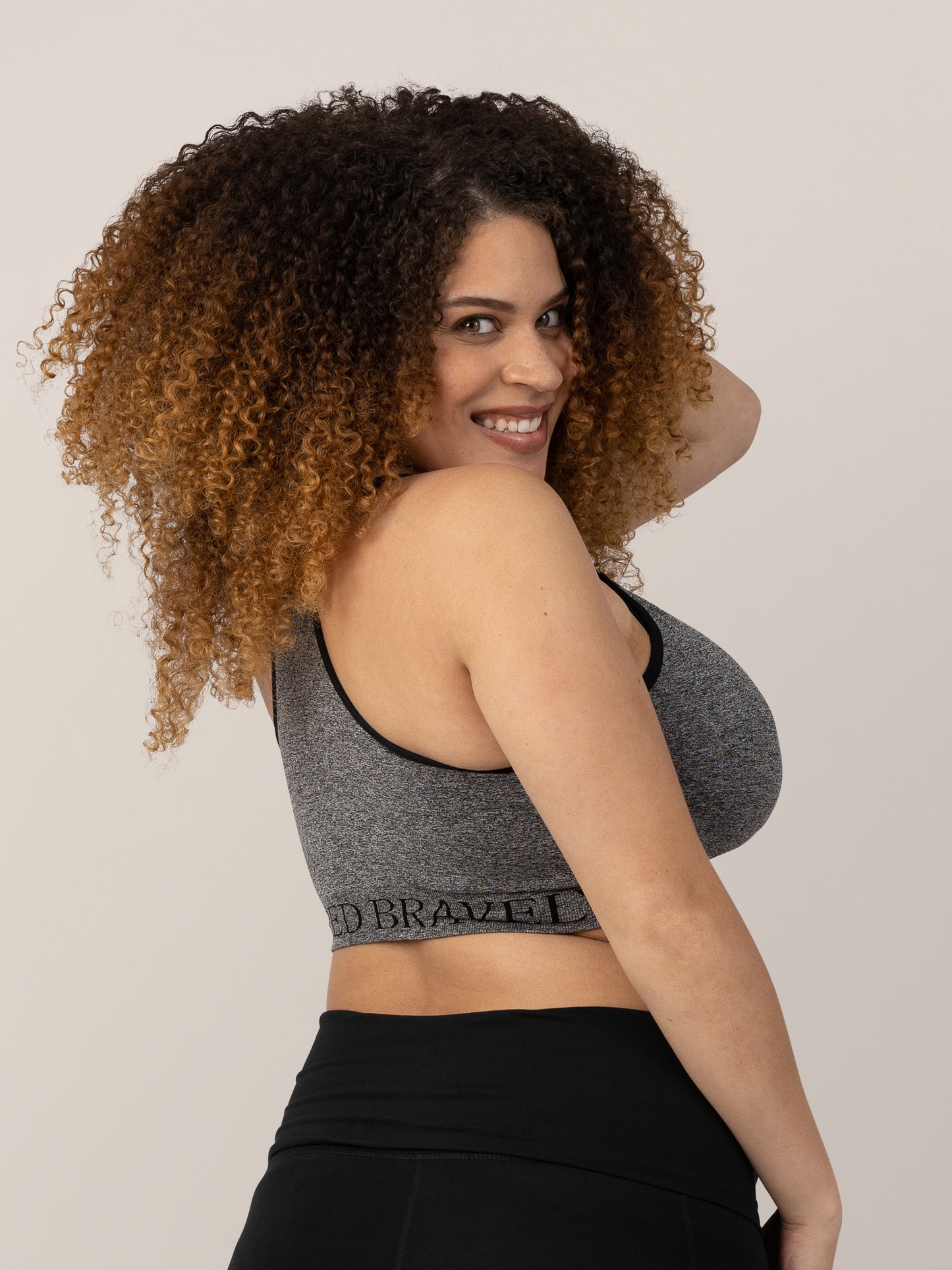 Model looking over her shoulder while wearing the Sublime® Nursing Sports Bra in Heather Grey.