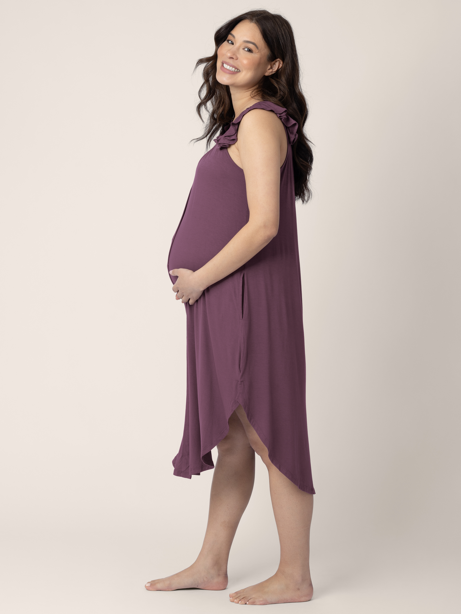 Side view of a model wearing the Ruffle Strap Labor & Delivery Gown in Burgundy Plum