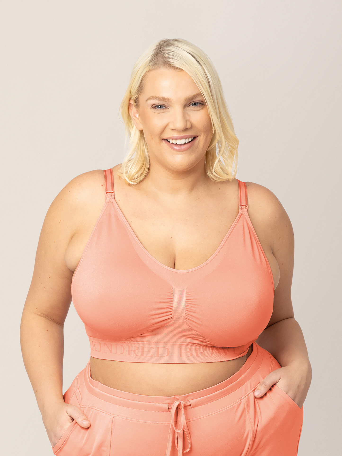 Busty model wearing the Simply Sublime® Nursing Bra in Vintage Coral with her hands in her pockets. @model_info:Lauren is wearing a 1X Busty. 
