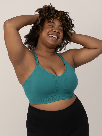 Model with her hands in her  hair wearing the Sublime® Hands-Free Pumping & Nursing Sports Bra in Teal. 