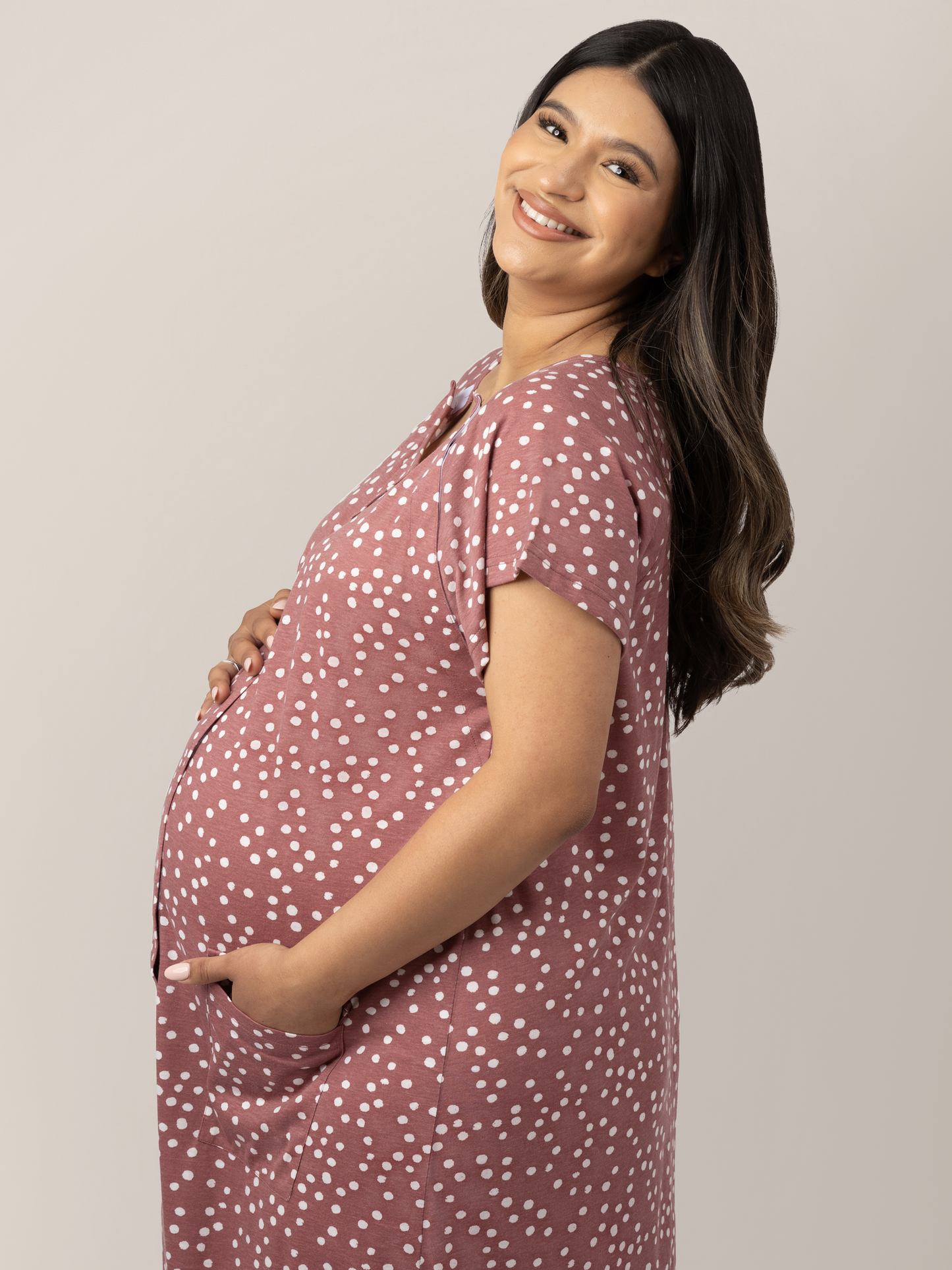 Closeup of the side view of a pregnant model wearing the Universal Labor & Delivery Gown in Rosewood Polka Dot