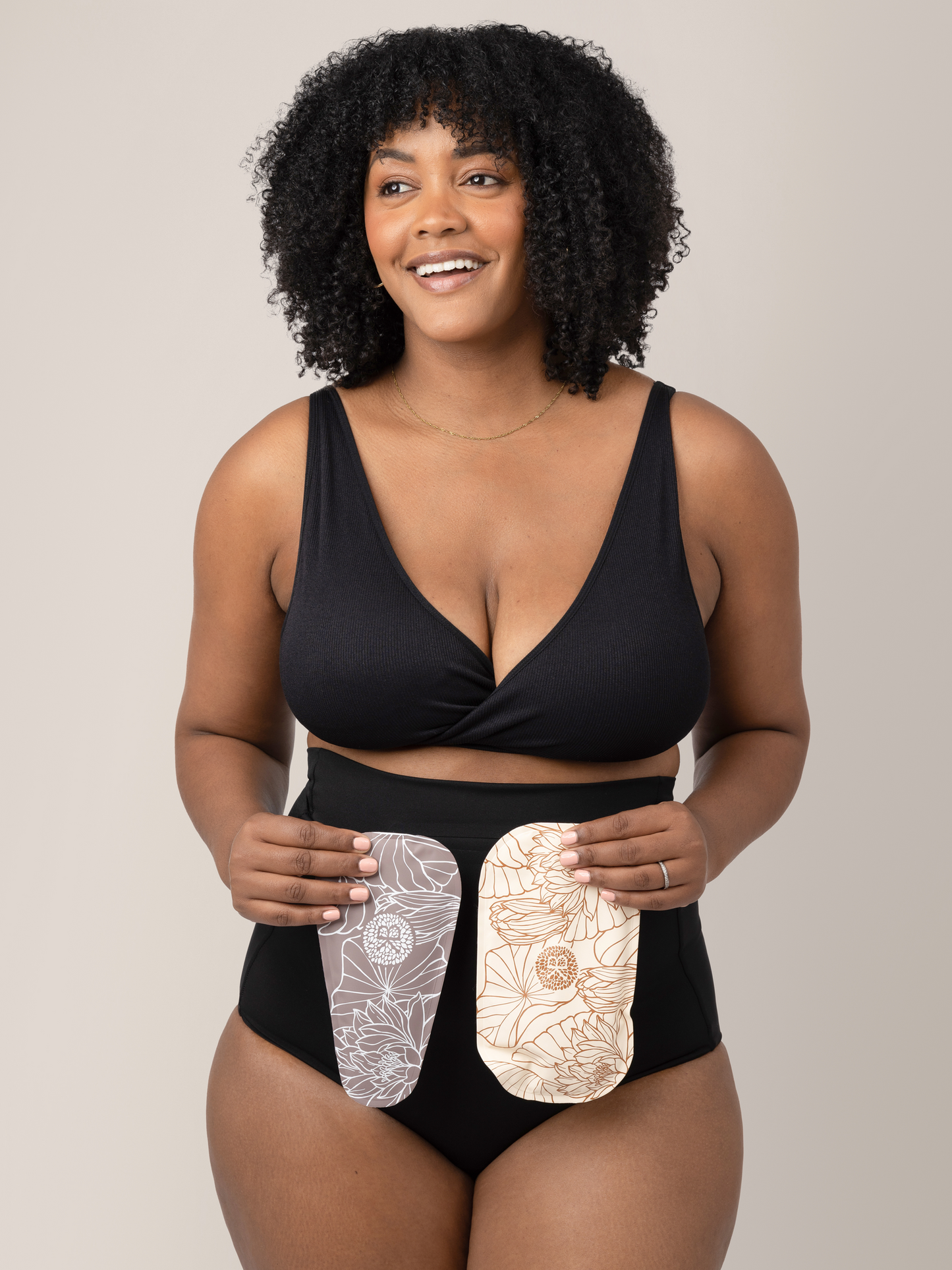 Model wearing the Soothing Fourth Trimester Underwear in Black wholding both forms of the soothing gel packs. 