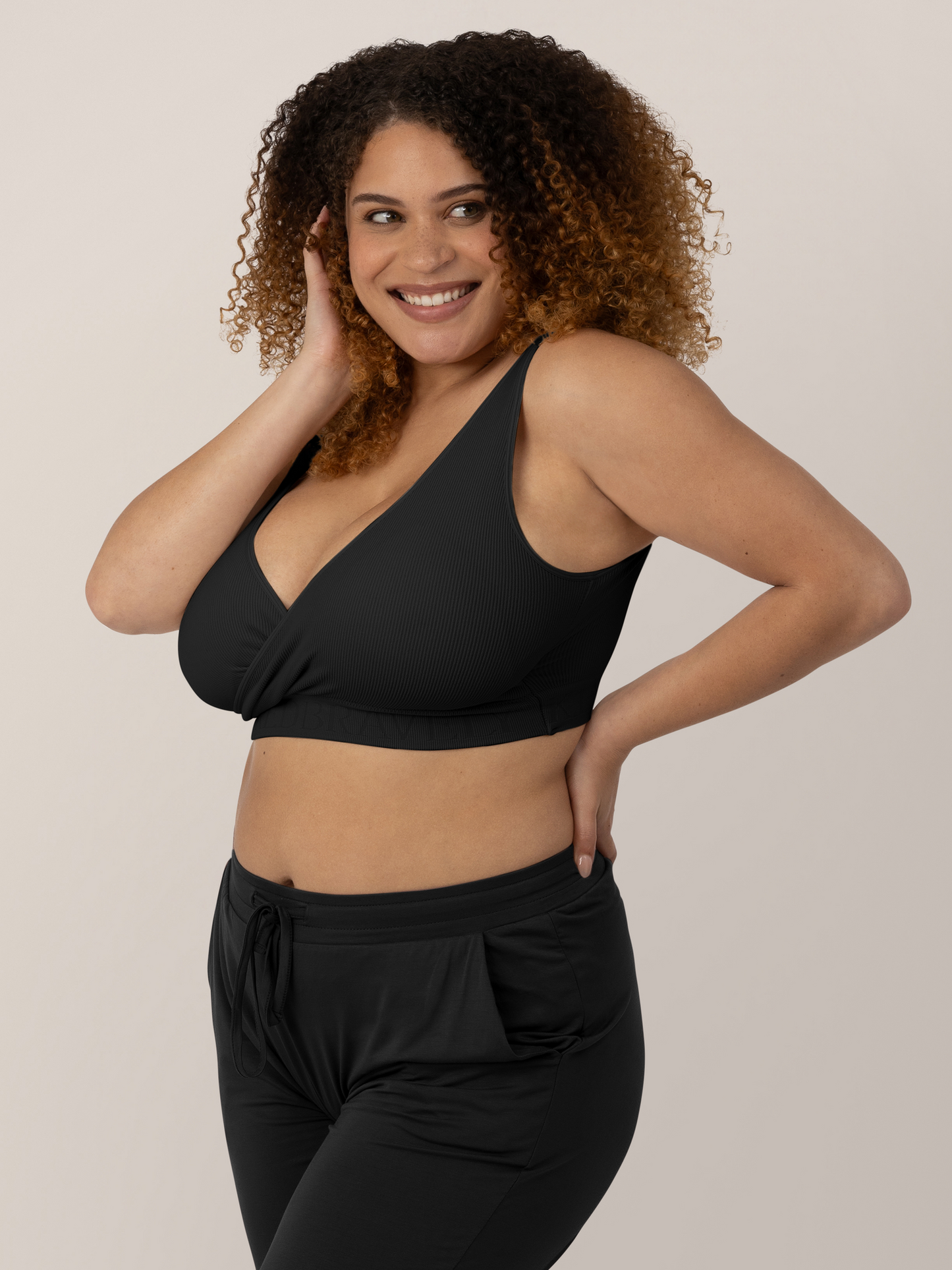 Model wearing the Sublime® Adjustable Crossover Nursing & Lounge Bra in Black with her hand on her hips and on her cheek.