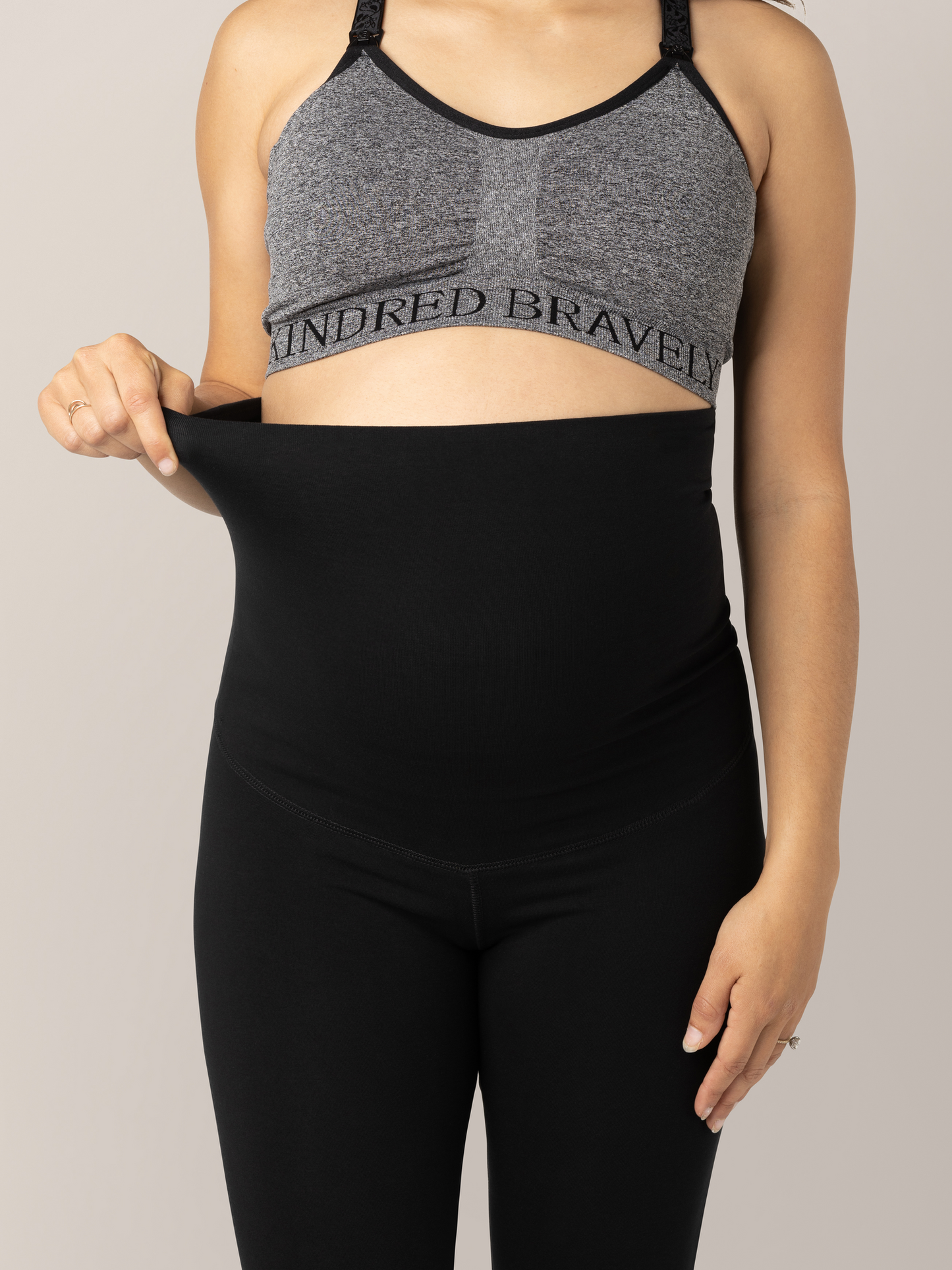 Close-up front view of waist band unfolded on the Cotton Maternity & Postpartum Footless Tight in black on pregnant model