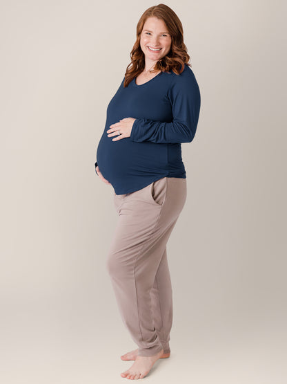 Pregnant model smiling at the camera and holding her stomach while wearing the Bamboo Maternity & Nursing Long Sleeve T-shirt in Navy 