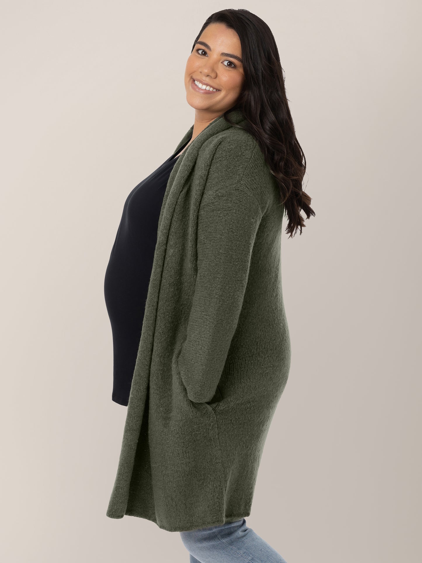 Side view of a pregnant model wearing the Chloe Cardigan Sweater in Thyme.