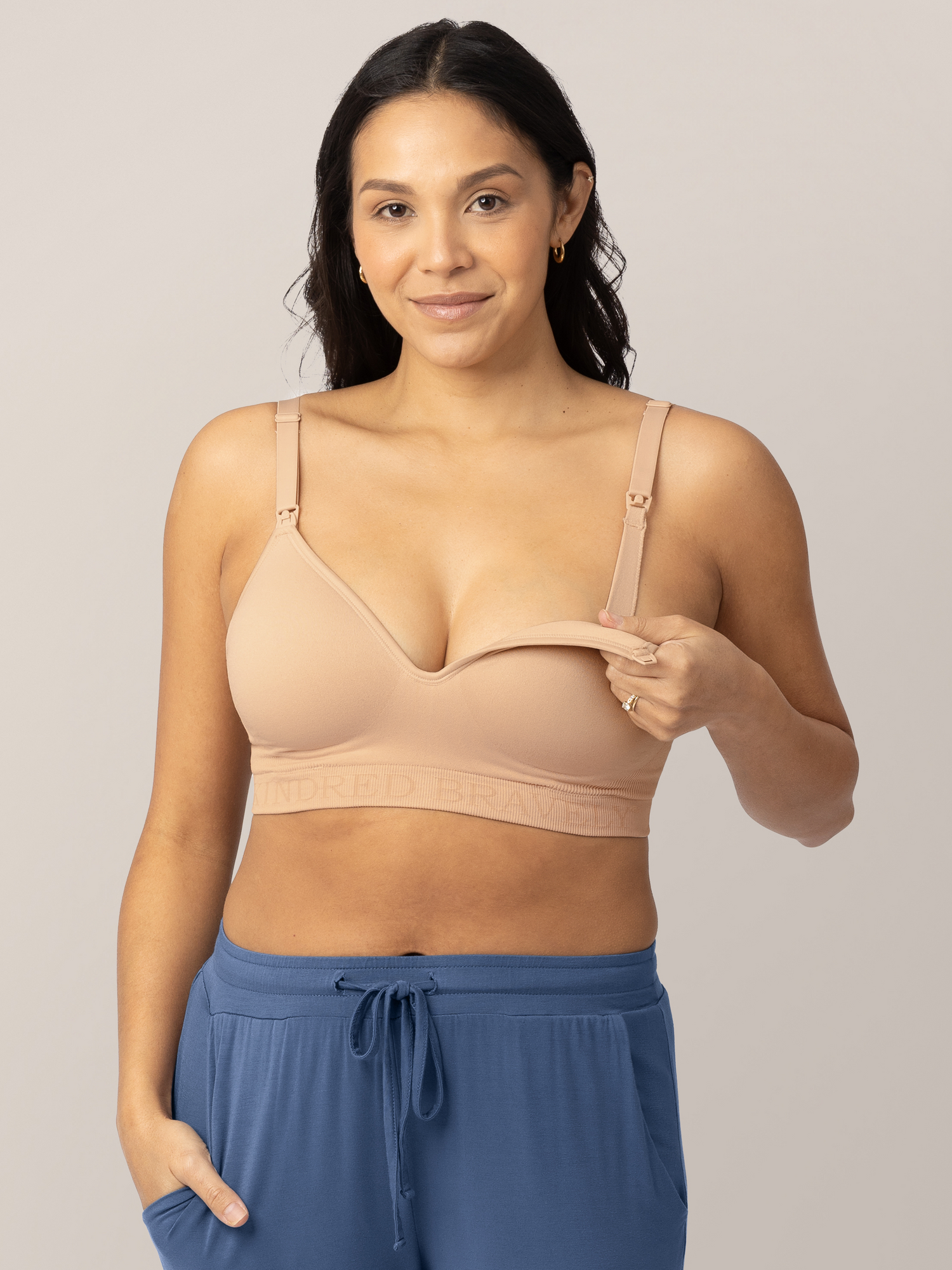 Model wearing the Signature Sublime® Contour Maternity & Nursing Bra in Beige holding down the easy clip down nursing access. 