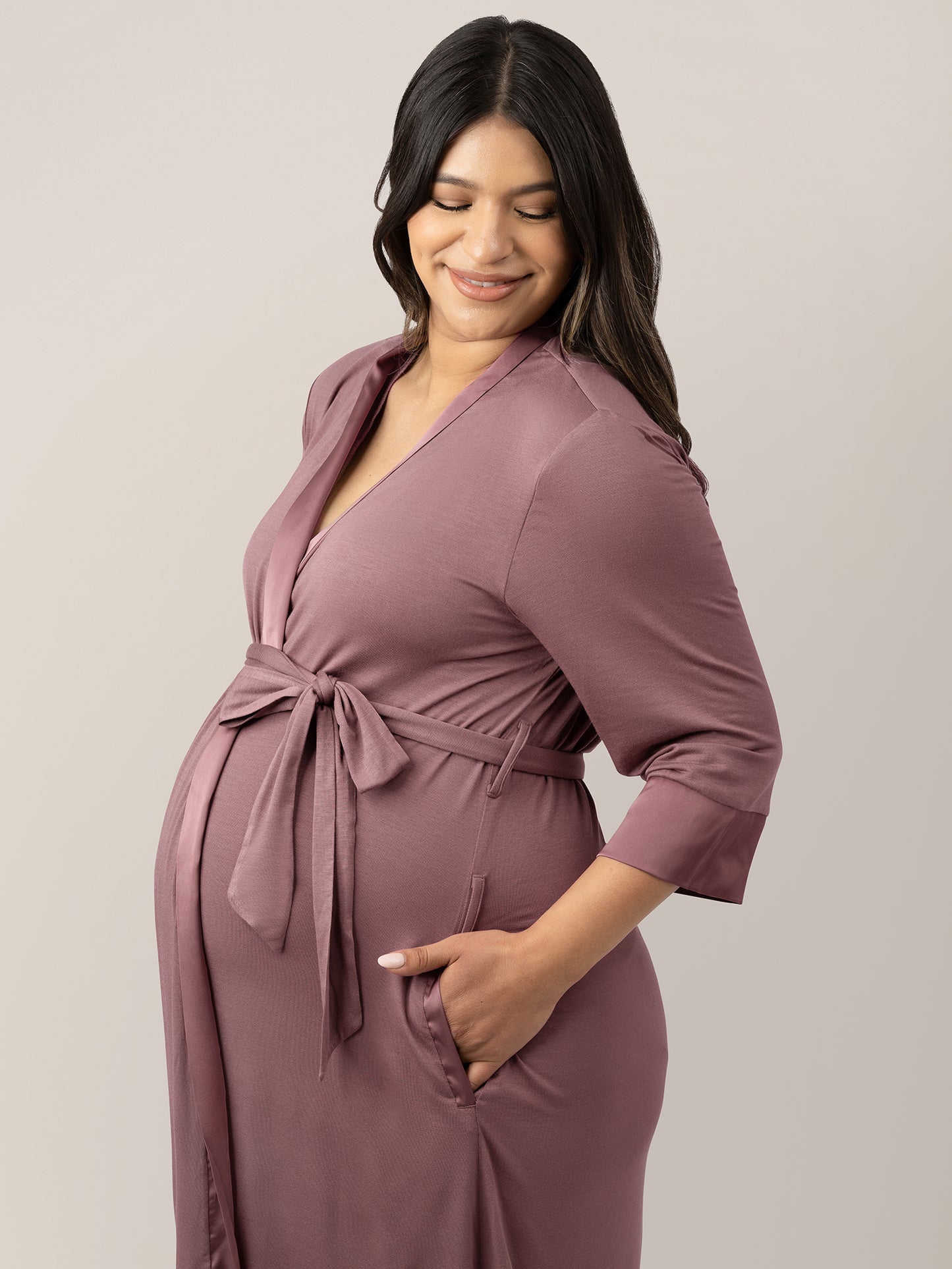Pregnant model wearing the Emmaline Robe in Twilight with her hands in her pockets.