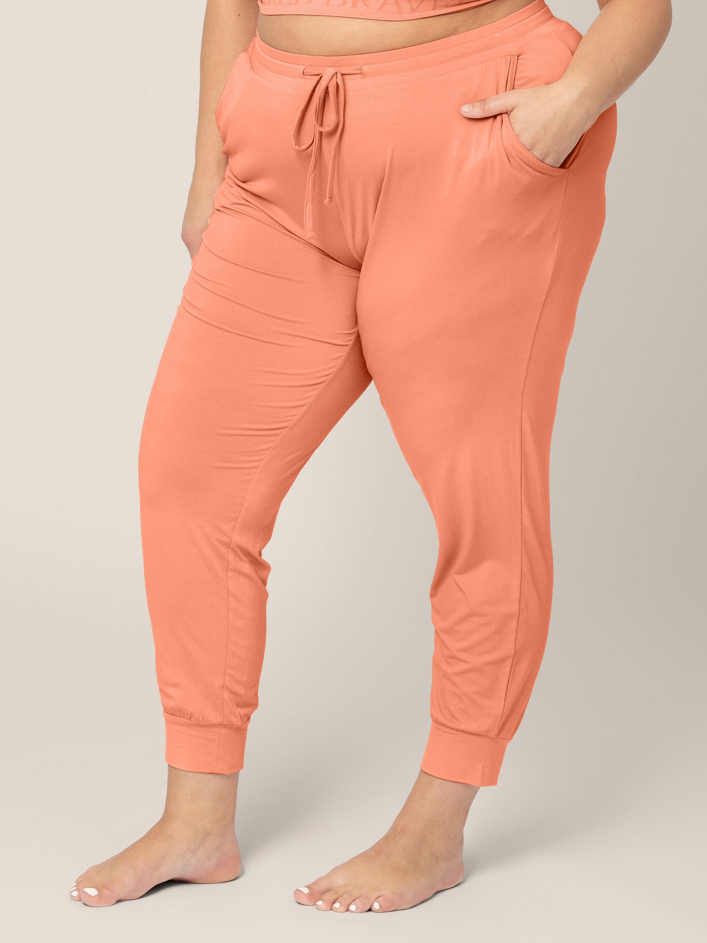 Three-quarters view of the bottom half of a model wearing the Model wearing the Everyday Lounge Joggers in Vintage Coral
