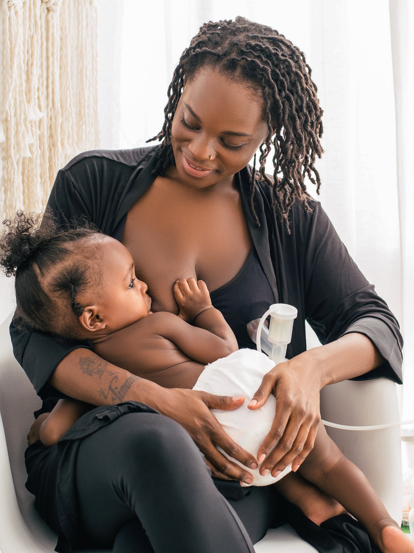 Model breastfeeding her baby while wearing the Sublime® Hands-Free Pumping & Nursing Bra in Black