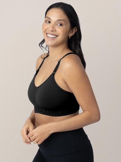 Model wearing the Sublime® Hands-Free Pumping & Nursing Sports Bra in Black with her hands near her stomach. @model_info:Julana is wearing a Small.