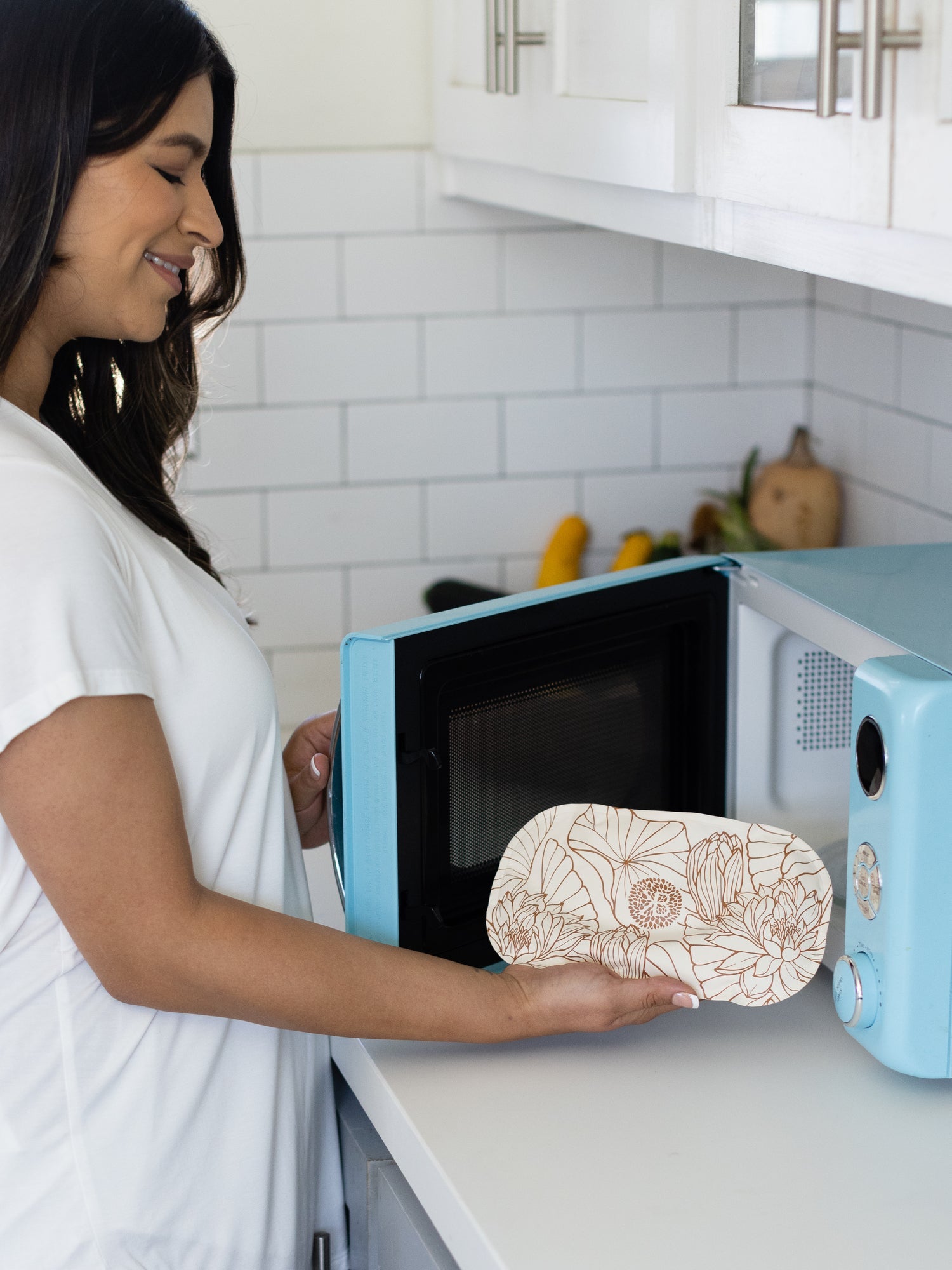 Model putting the Soothing Belly & Back Gel Pack in the microwave.