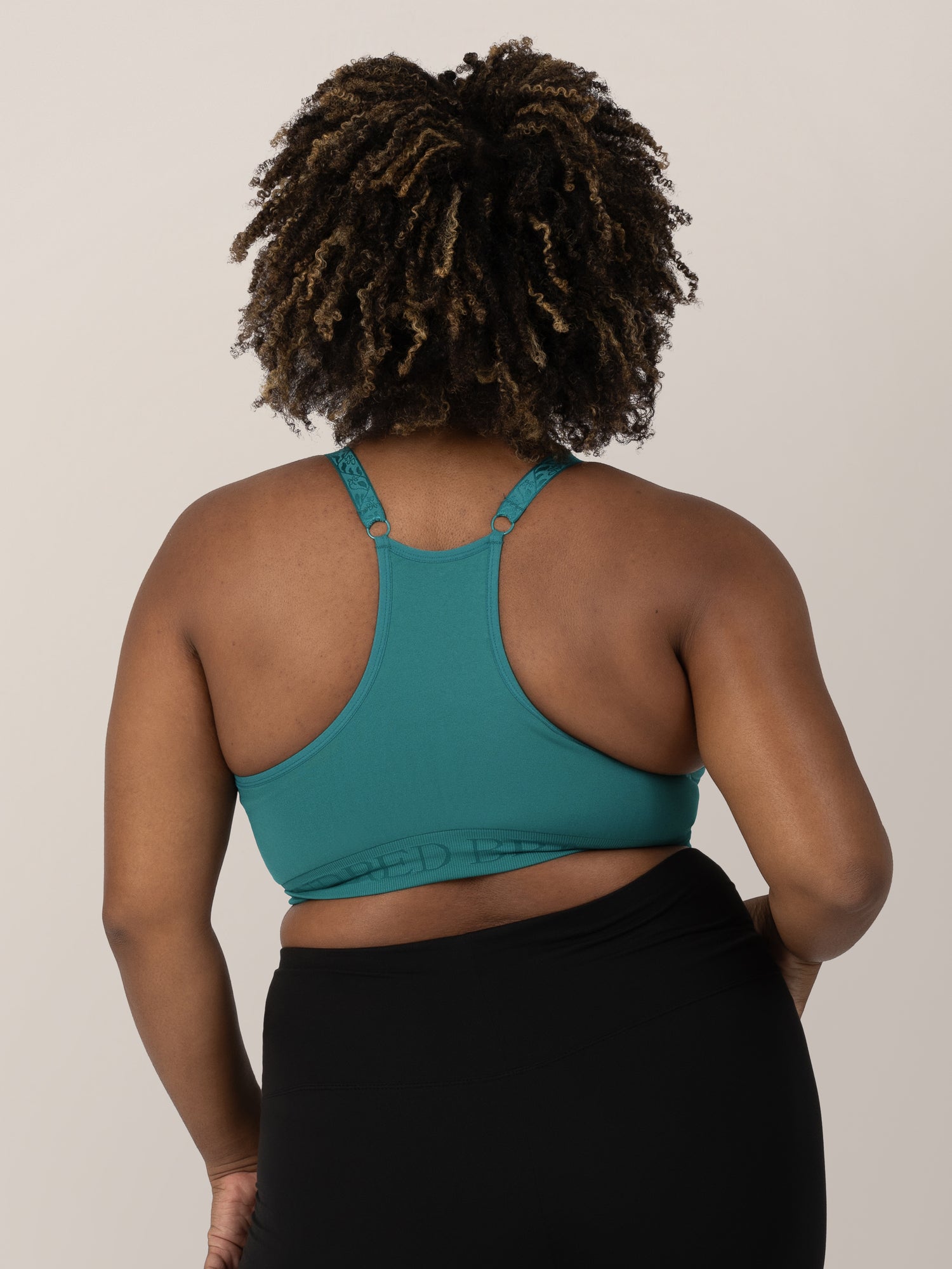 Back of a model wearing teh Sublime® Hands-Free Pumping & Nursing Sports Bra in Teal.