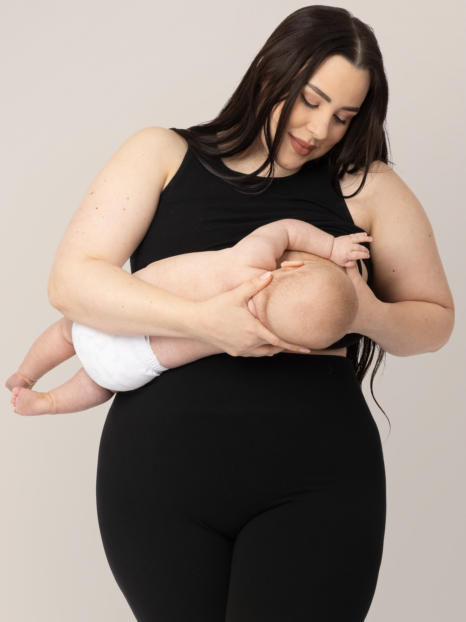 Model wearing the Sublime Bamboo Maternity & Nursing Longline Bra in Black and holding and nursing her infant.