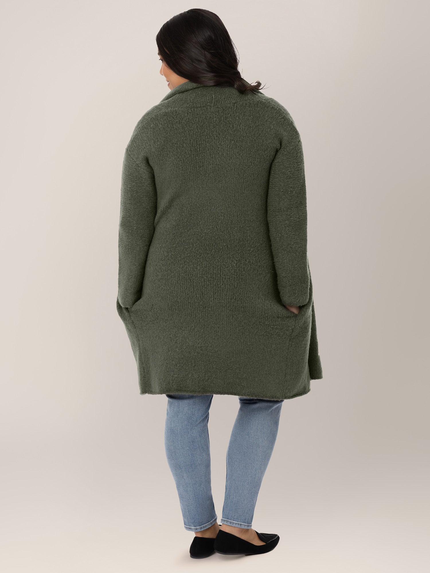 Back view of a pregnant model wearing the Chloe Cardigan Sweater in Thyme. 