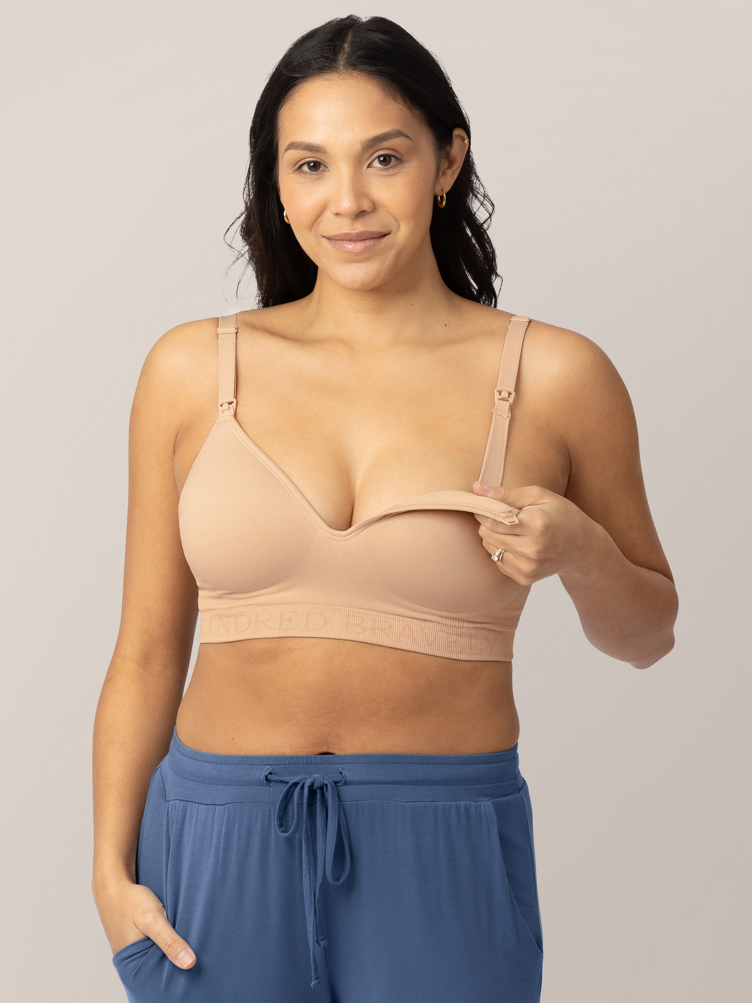 Model wearing the Signature Sublime® Contour Maternity & Nursing Bra in Beige holding down the easy clip down nursing access.