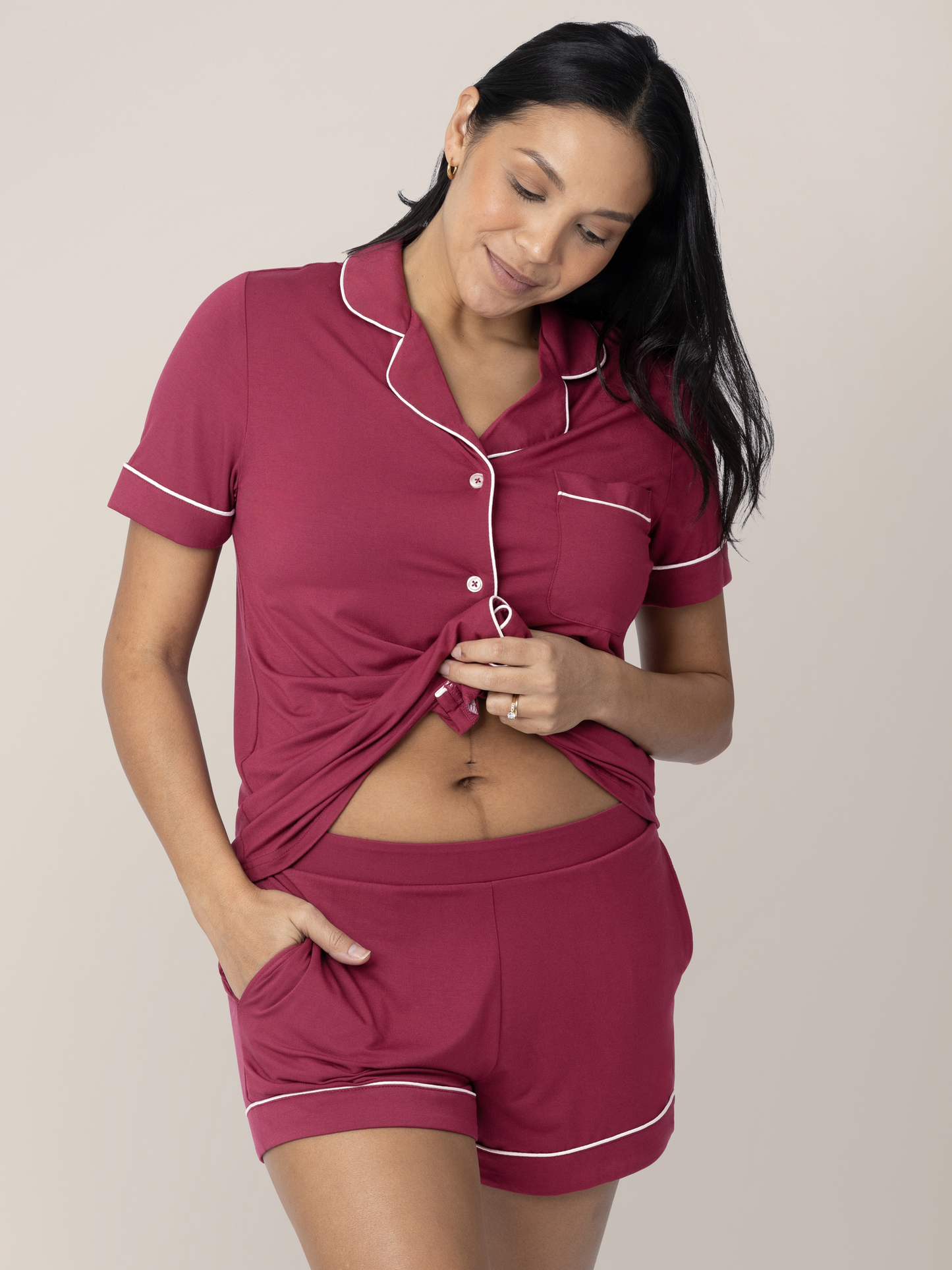 Model wearing the Clea Bamboo Short Sleeve Pajama Set in Deep Berry holding up the shirt. 