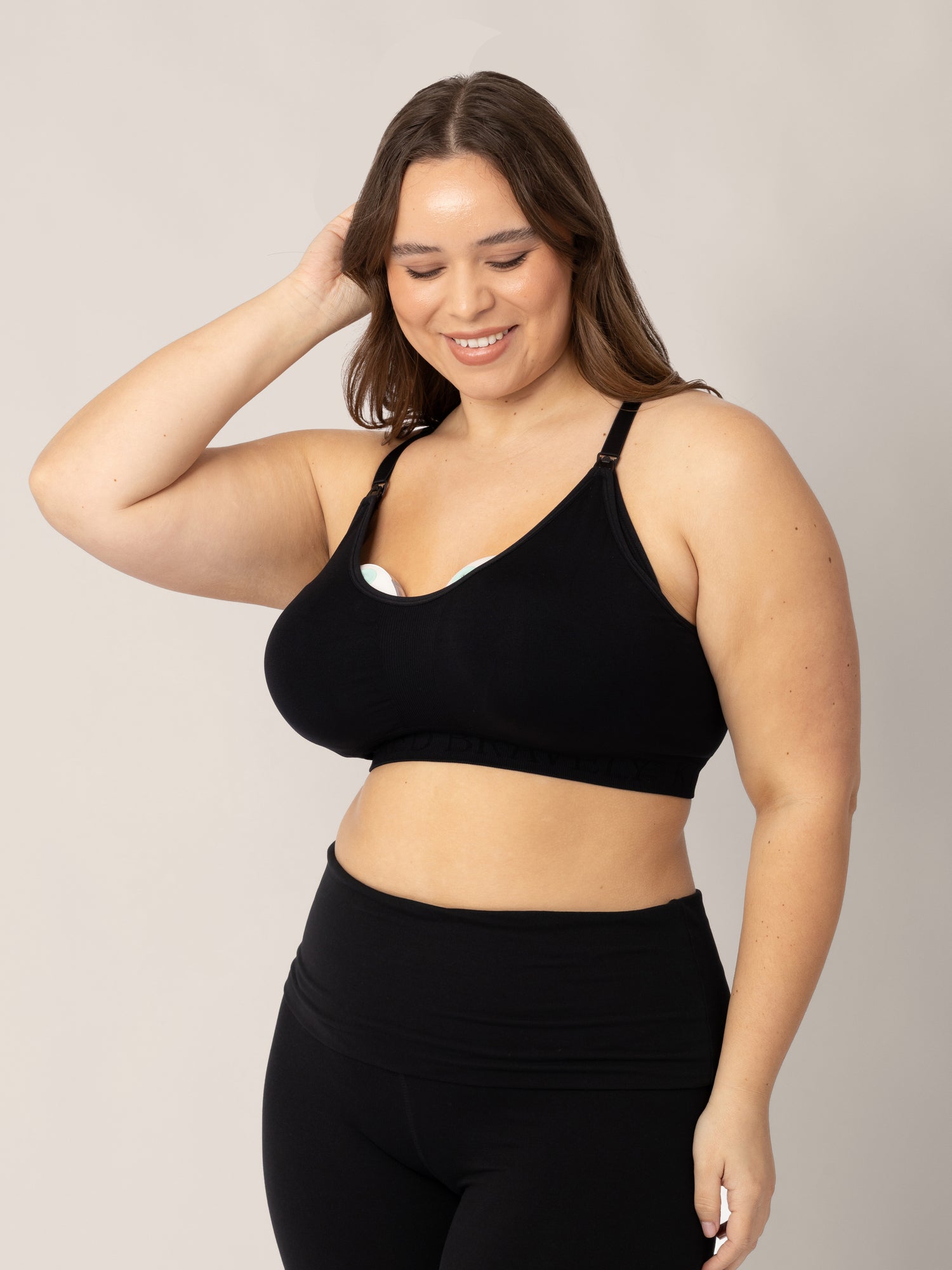 Model with two pumps in her Sublime® Nursing Sports Bra in Black with her hand on her head.
