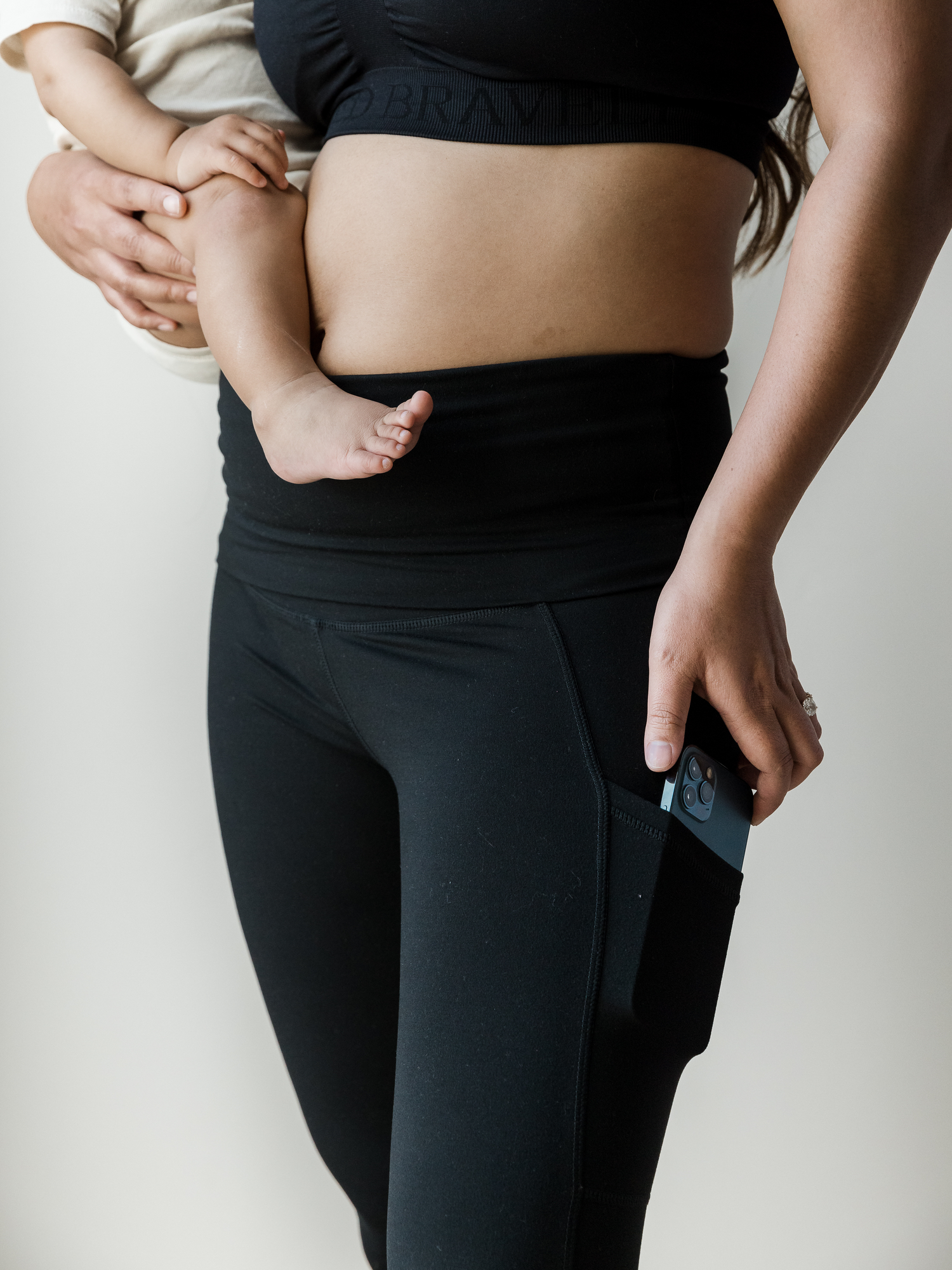 Closeup of a model wearing the Louisa Maternity & Postpartum  Legging in Black with her phone in the pocket.