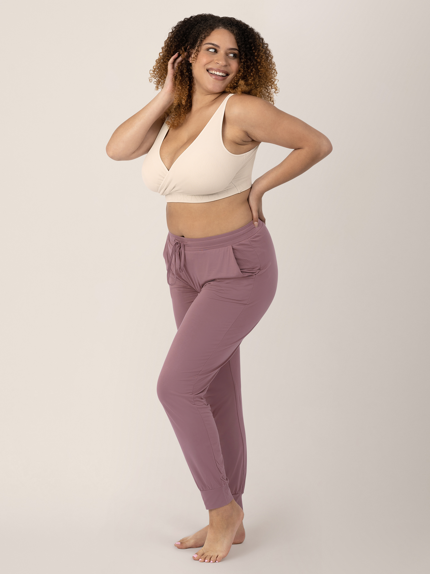 Model wearing the Sublime® Adjustable Crossover Nursing & Lounge Bra in Stone with her hand on her hip and in her hair. 