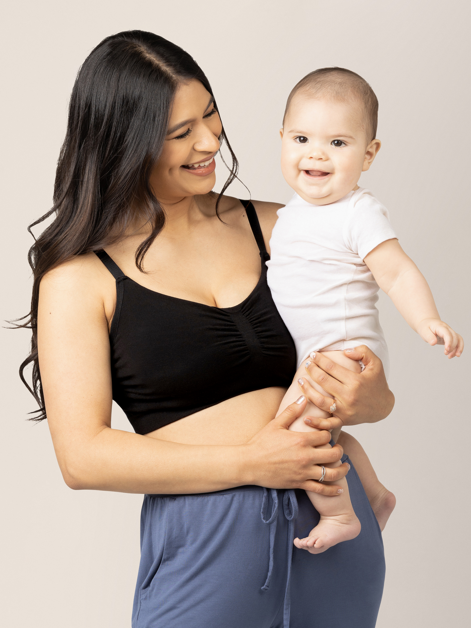 Model holding her baby while wearing the Sublime® Bamboo Hands-Free Pumping Lounge & Sleep Bra in Black