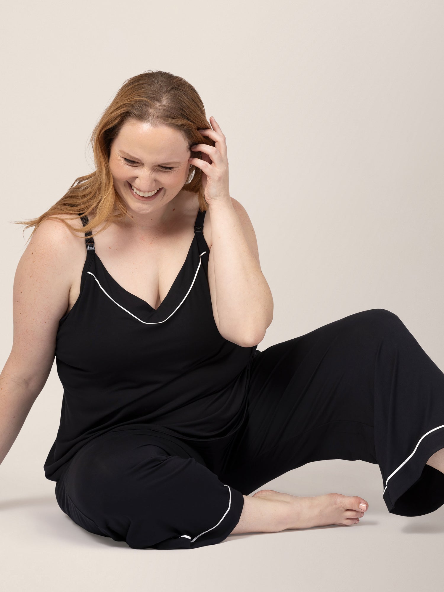 Model sitting on the ground while wearing the Clea Bamboo Nursing Tank & Capri Pajama Set in Black