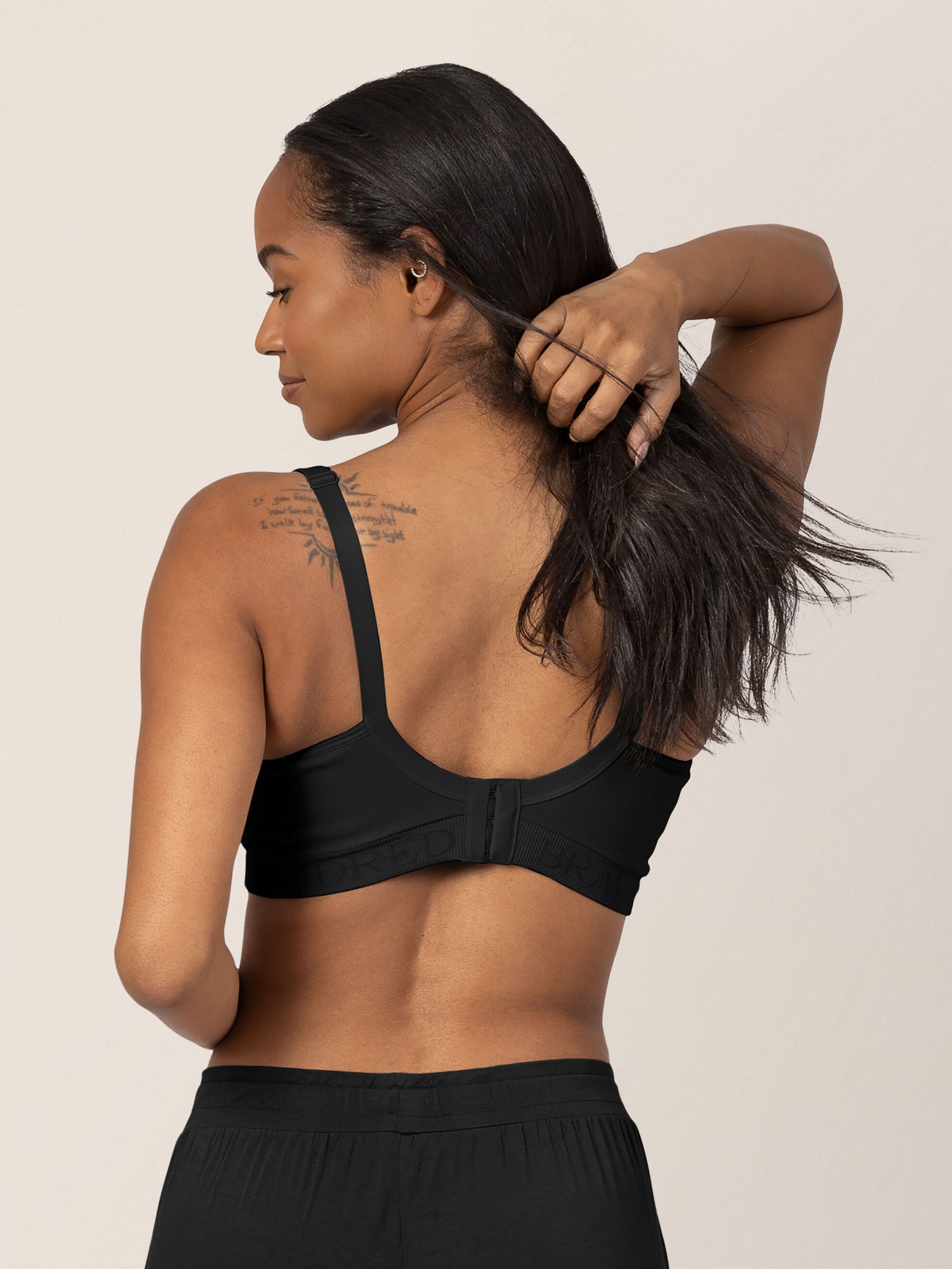 Back of a model wearing the Signature Sublime® Contour Maternity & Nursing Bra in Black as she holds her hair back.