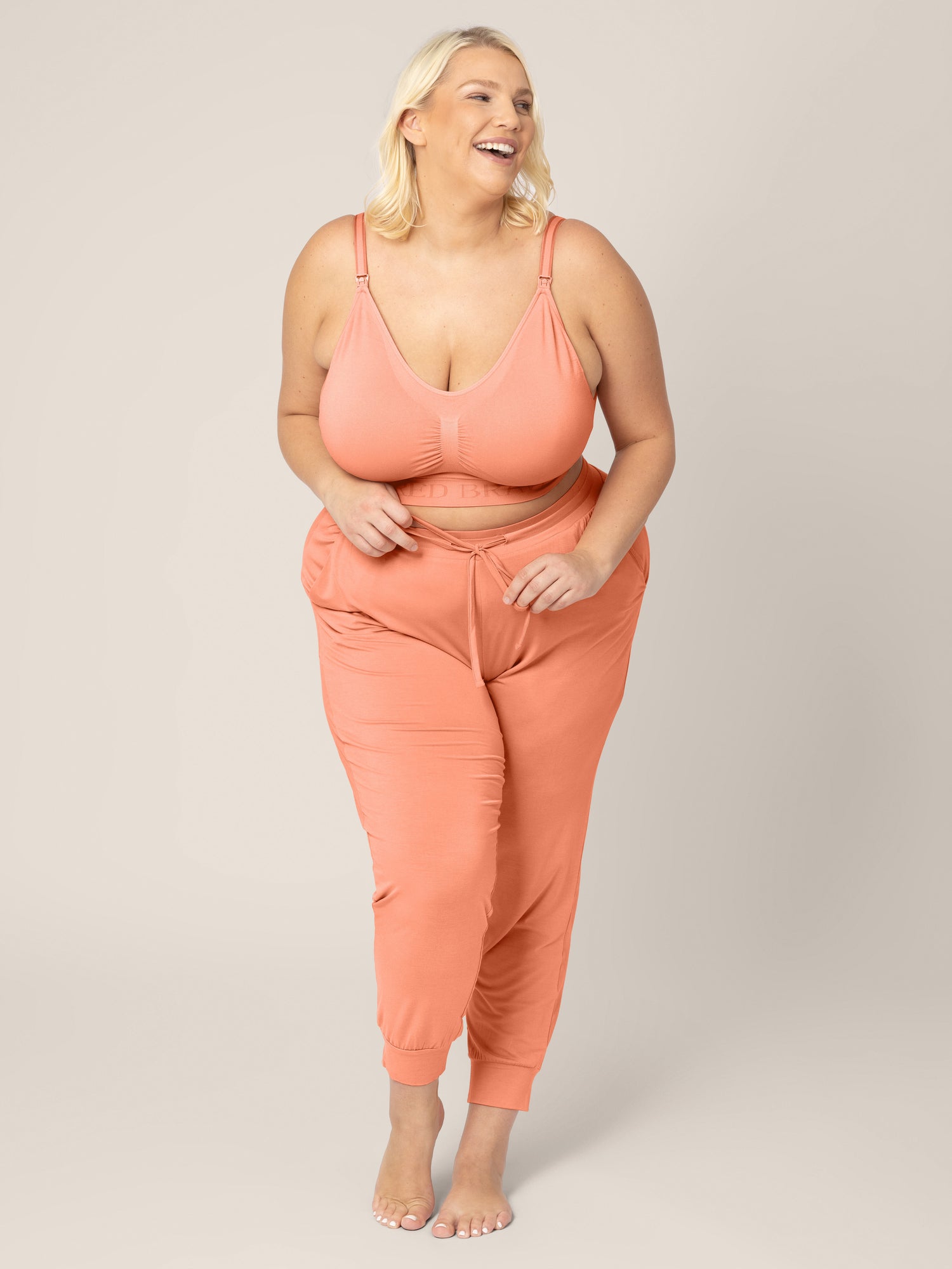 Full body smiling model wearing the Everyday Lounge Joggers in Vintage Coral