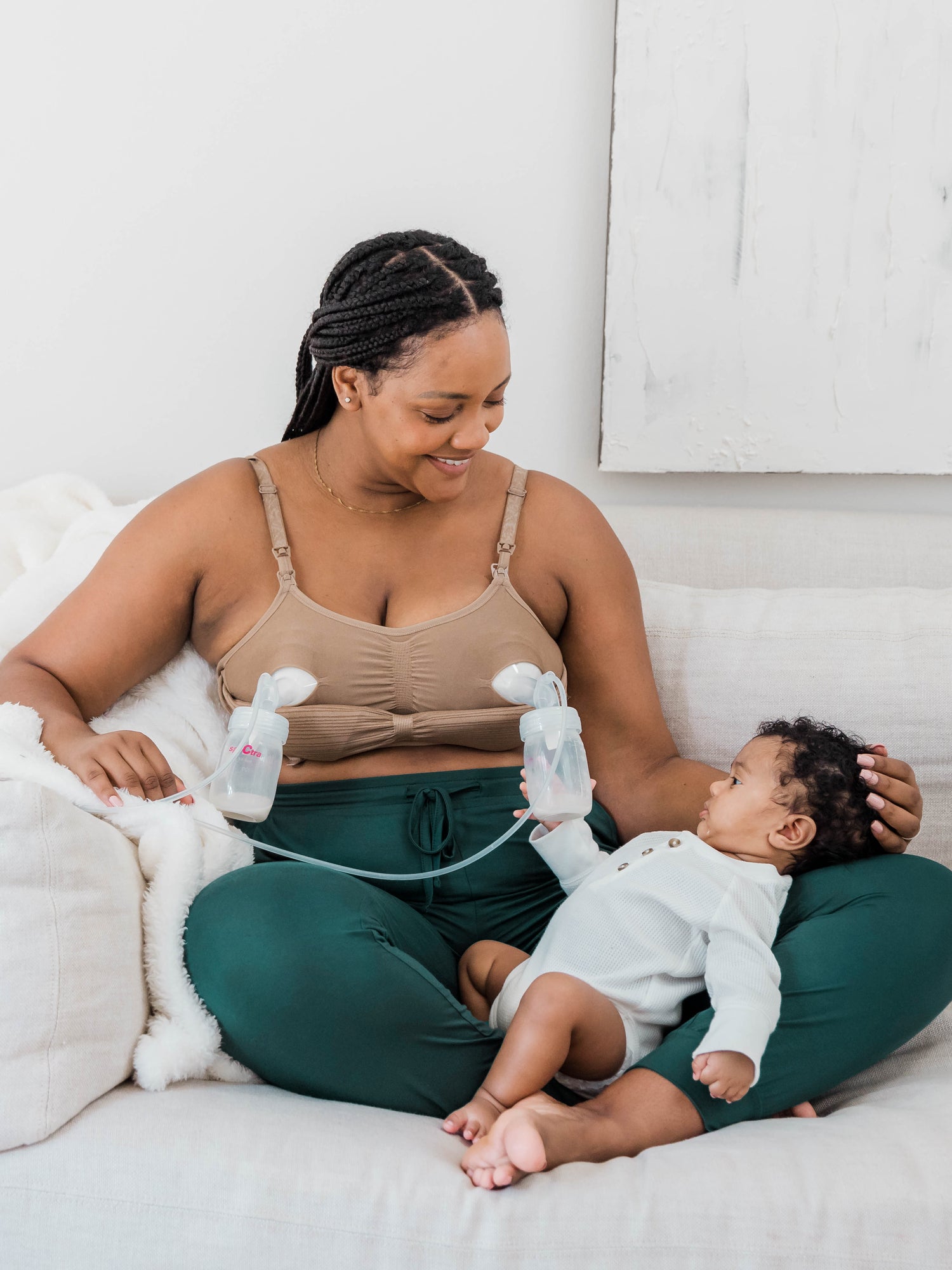 Model with her baby in her lap wearing the Sublime® Hands-Free Pumping & Nursing Bra in Latte @model_info:Roxanne is wearing a Large.