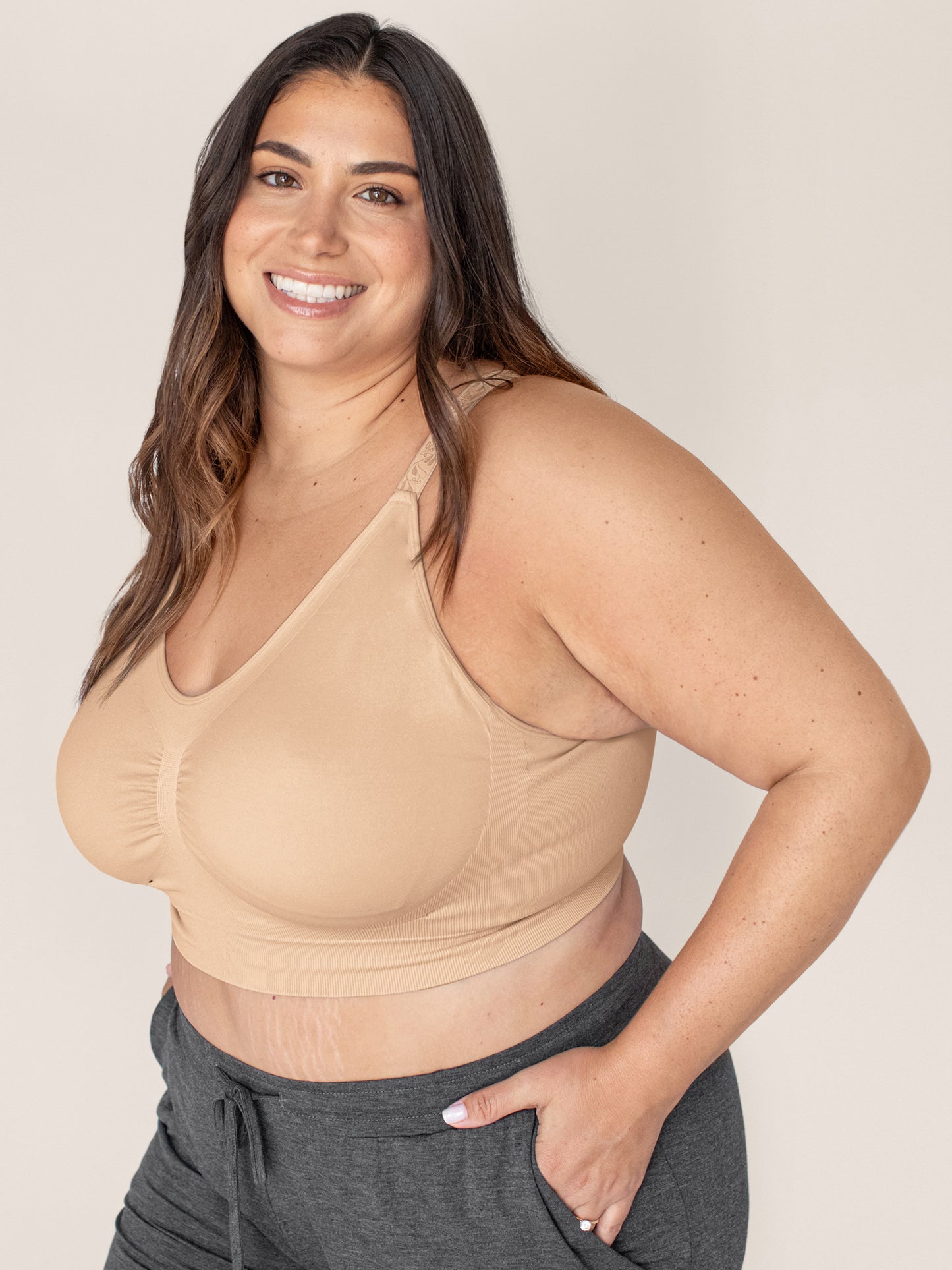 Three quarters view of a model wearing the Nellie Sublime® Wireless Bra in Beige with her hands in her pockets. 