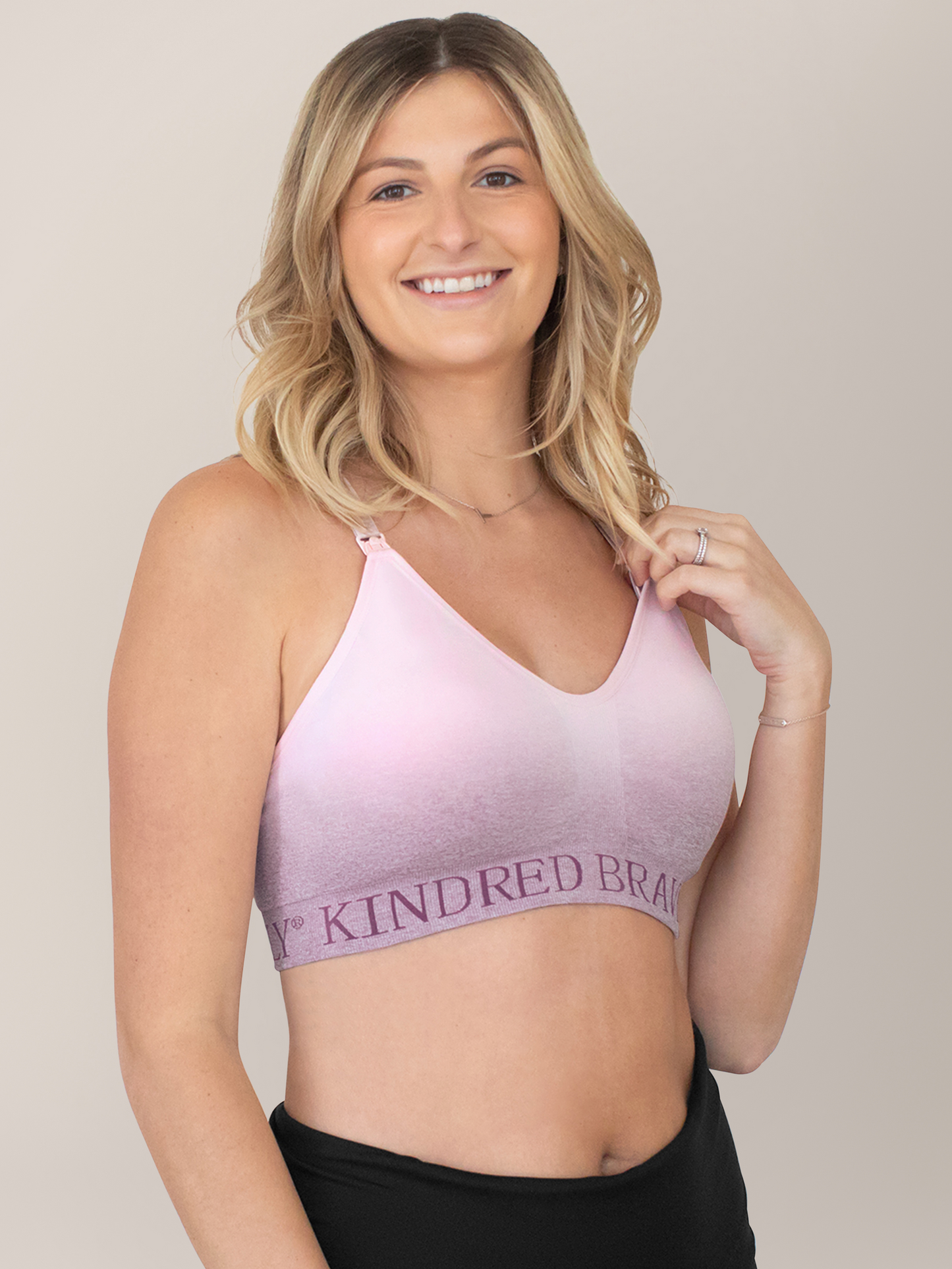 Model smiling at the camera while wearing teh Sublime® Hands-Free Pumping & Nursing Sports Bra in Ombre Purple.