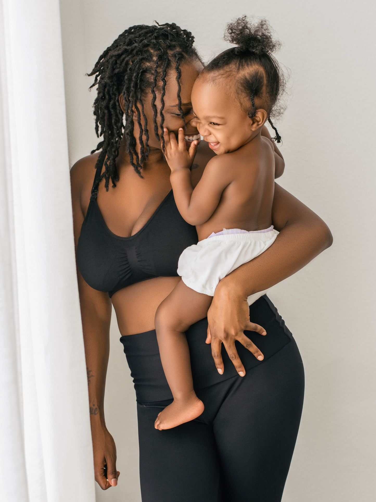 Model holding her baby on her hip while wearing the Simply Sublime® Nursing Bra in Black @model_info:Adrinne is wearing a Medium.