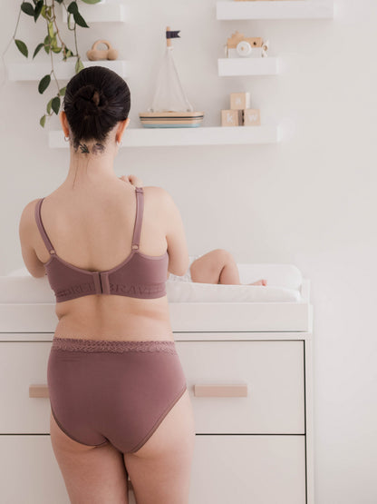 Back view of a model changing her baby on a changing table while wearing the High Waisted Postpartum underwear in Dusty Hues.  @model_info:Kianna is wearing a Small.
