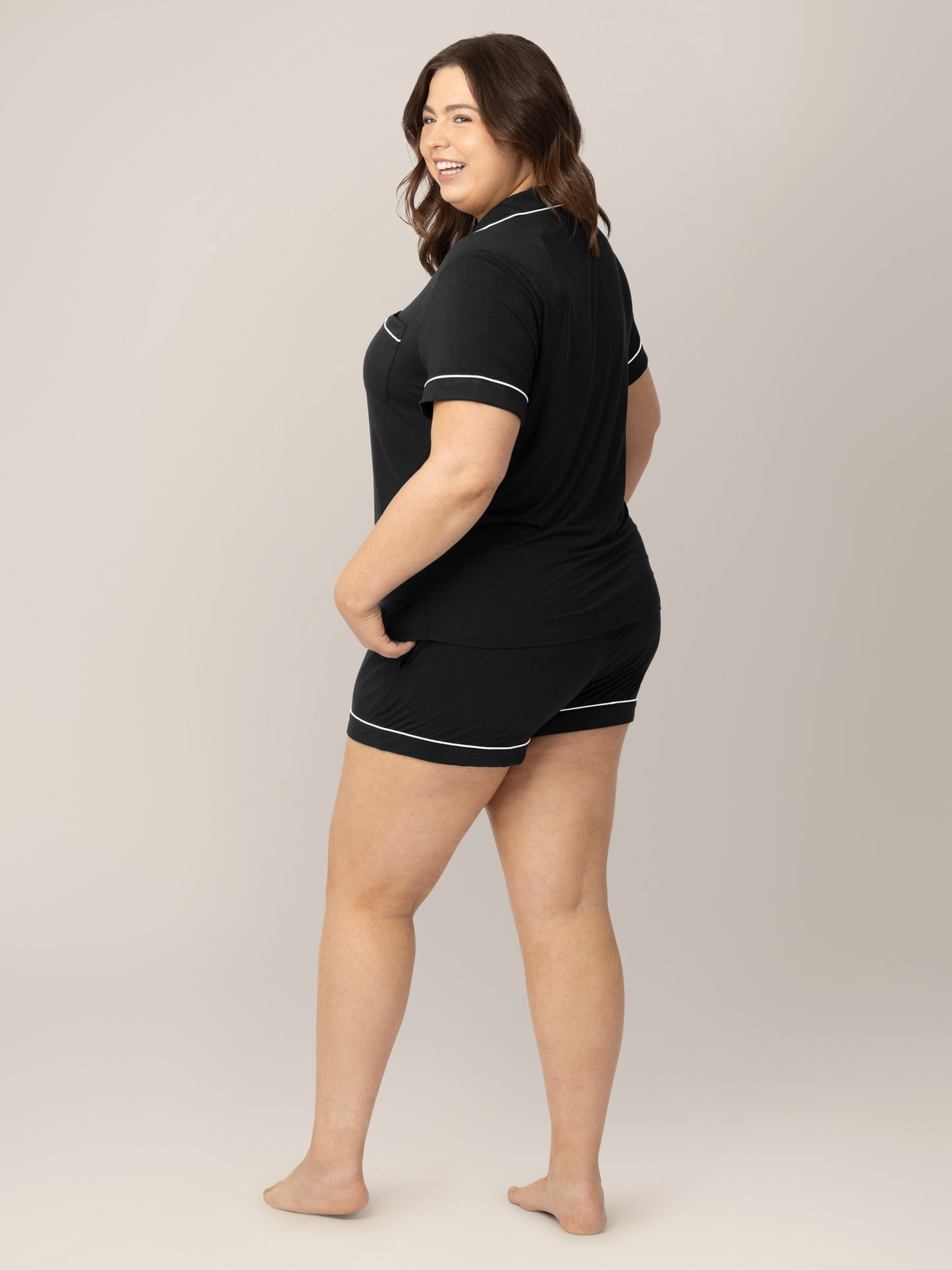 Back of a model wearing the Clea Bamboo Short Sleeve Pajama Set in Black with her hand on her hip. 