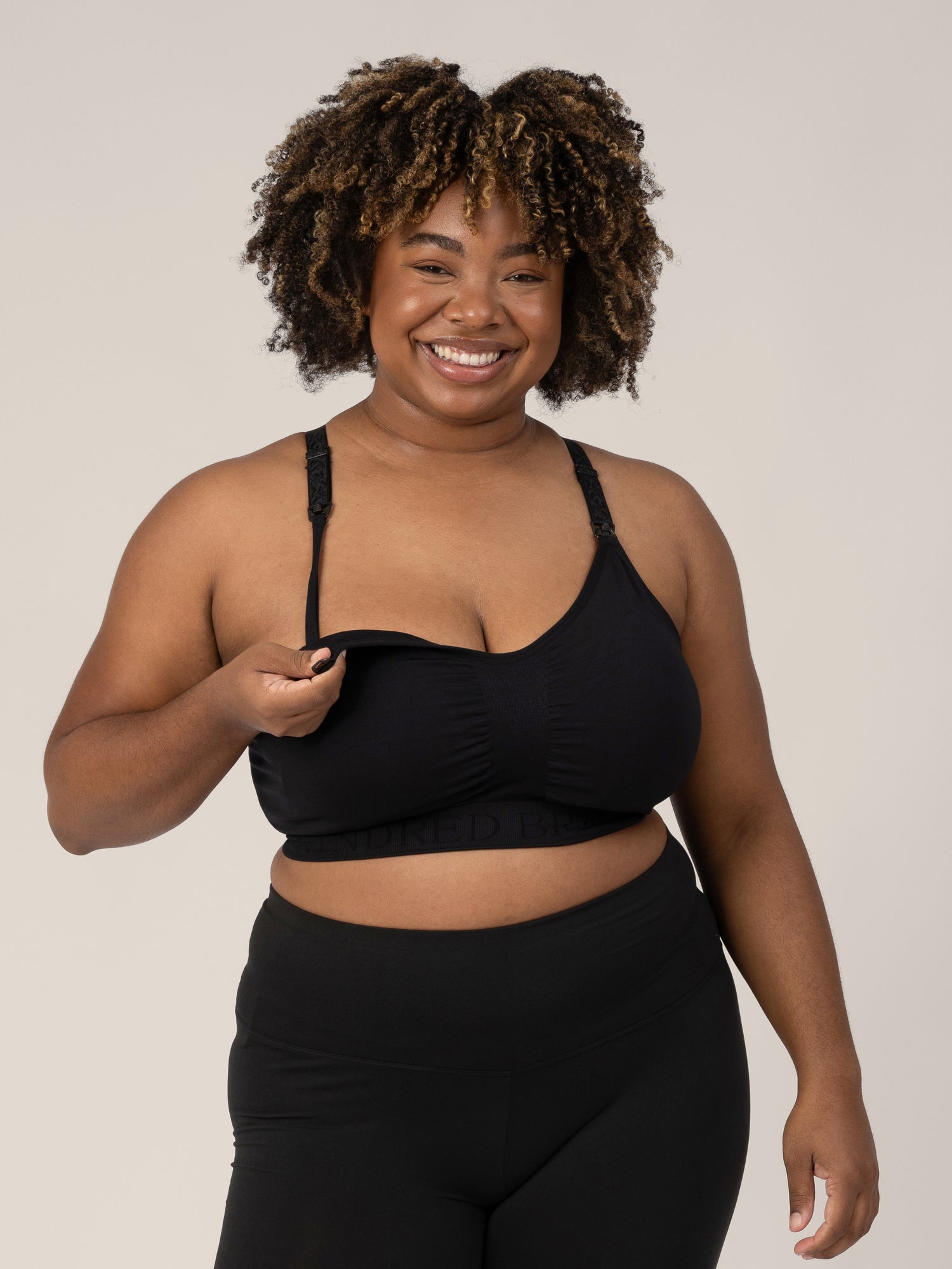 Model wearing the Sublime® Nursing Sports Bra in Black with her hand on the clip down nursing access.