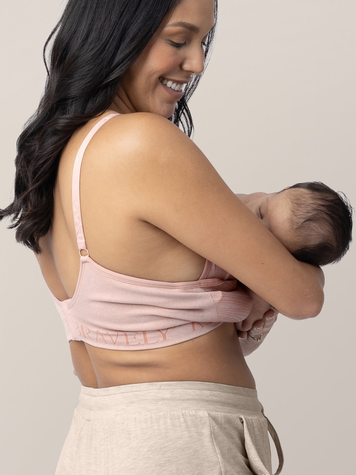 Model breastfeeding her baby while wearing the Sublime® Hands-Free Pumping & Nursing Bra in Pink Heather