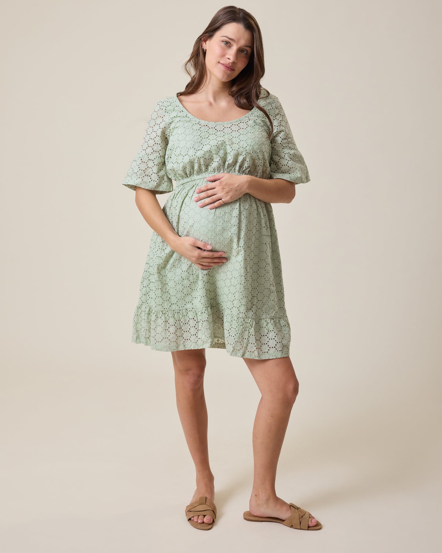 Pregnant woman wearing Dahlia Eyelet Maternity & Nursing Dress in aqua mist against a beige background@model_info:Elliana is 5'7" and wearing a Medium.