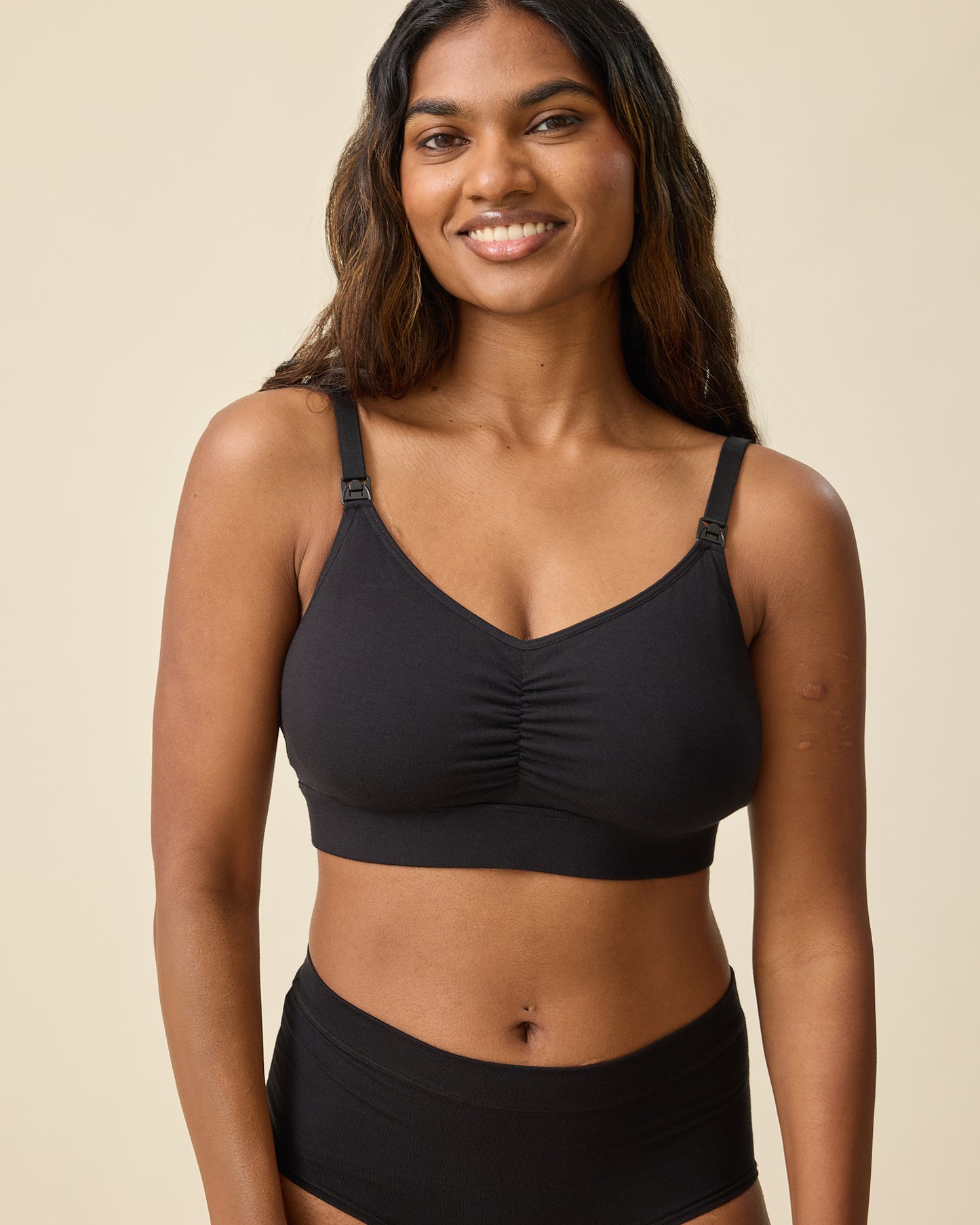 Model is wearing Every Stage Nursing Bra in Black on a beige background @model_info:Sahana is wearing a Small.