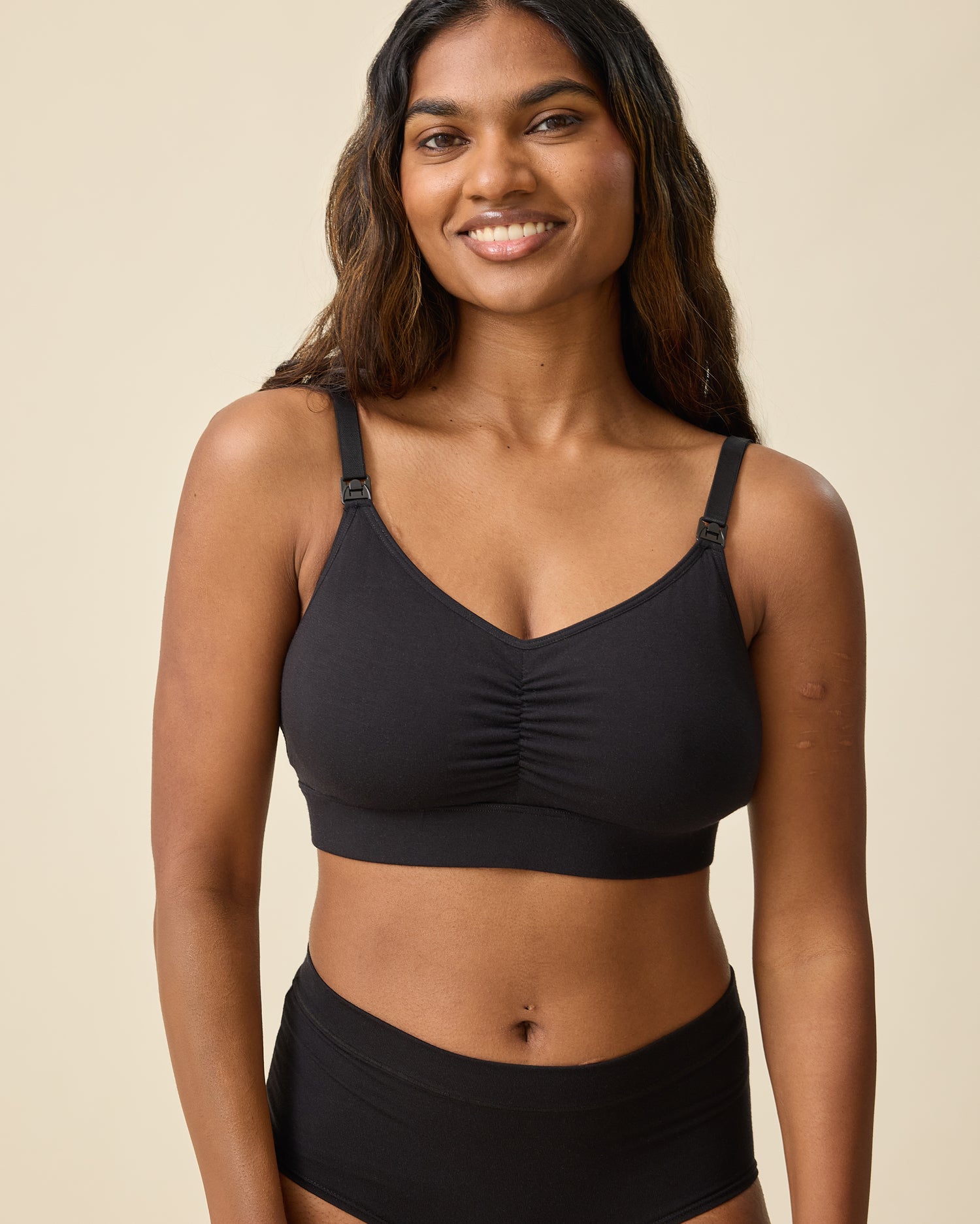 Model is wearing Every Stage Nursing Bra in Black on a beige background @model_info:Sahana is wearing a Small.