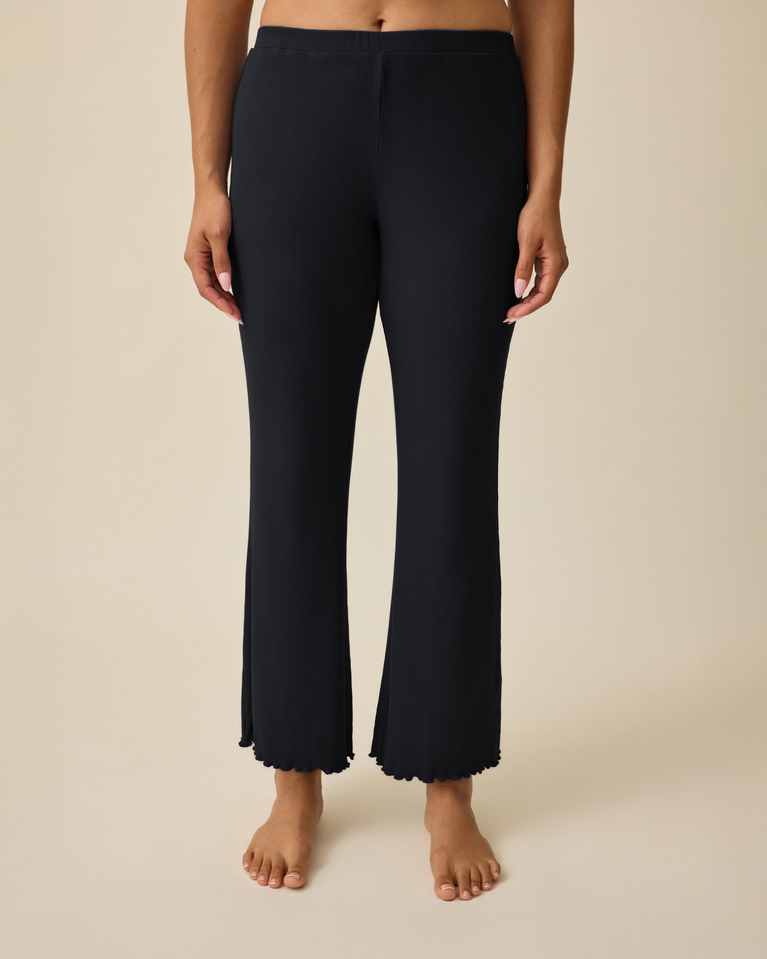 Model is wearing Ribbed Modal Lounge Pant in Black on a beige background. @model_info:Mei is 5'8" and wearing Small.