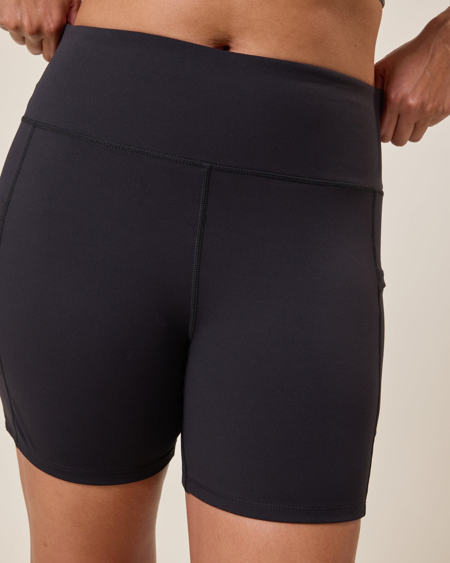 Stevie Active Postpartum Bike Short in black worn by a person on a beige background@model_info:Alana is 5'7" and wearing a Large.