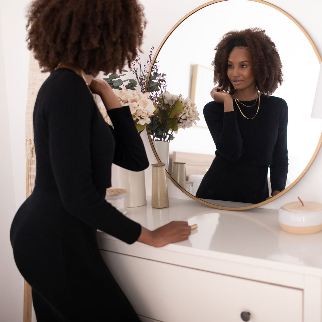 Model looking in the mirror while wearing the 2-in-1 Maternity & Nursing Midi Dress in Black