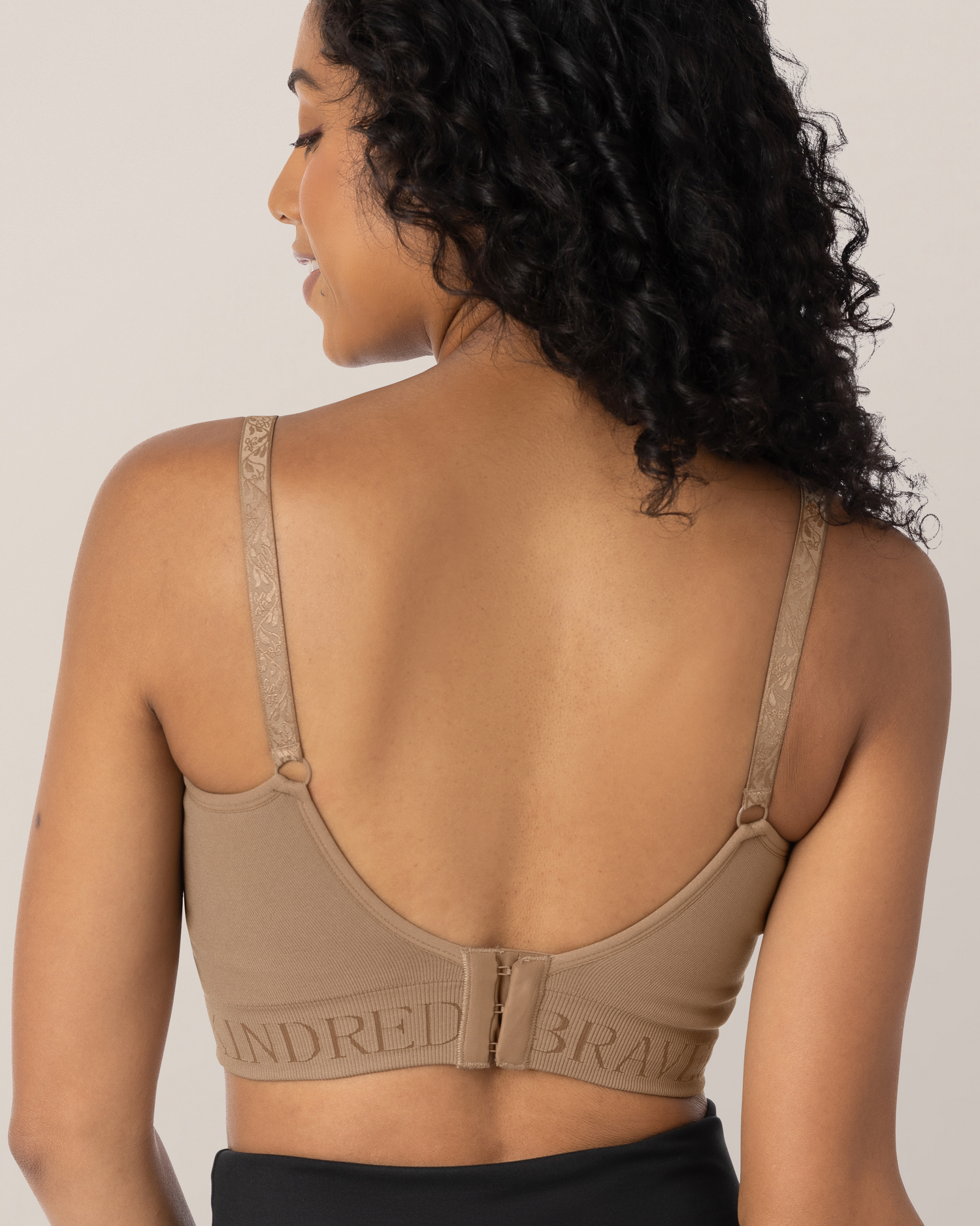 Woman wearing a latte bra on a plain background