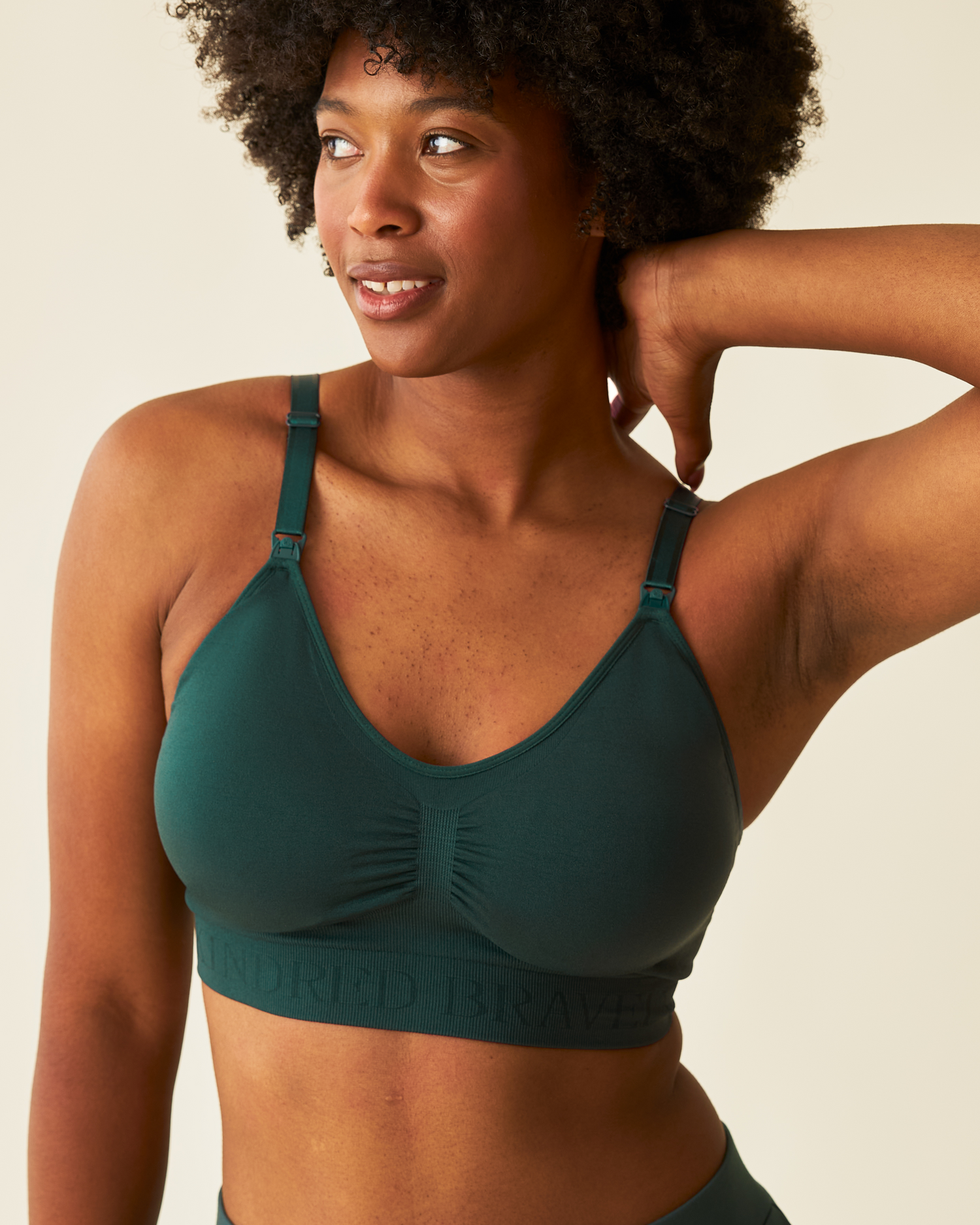 Woman wearing a green bra against a beige background